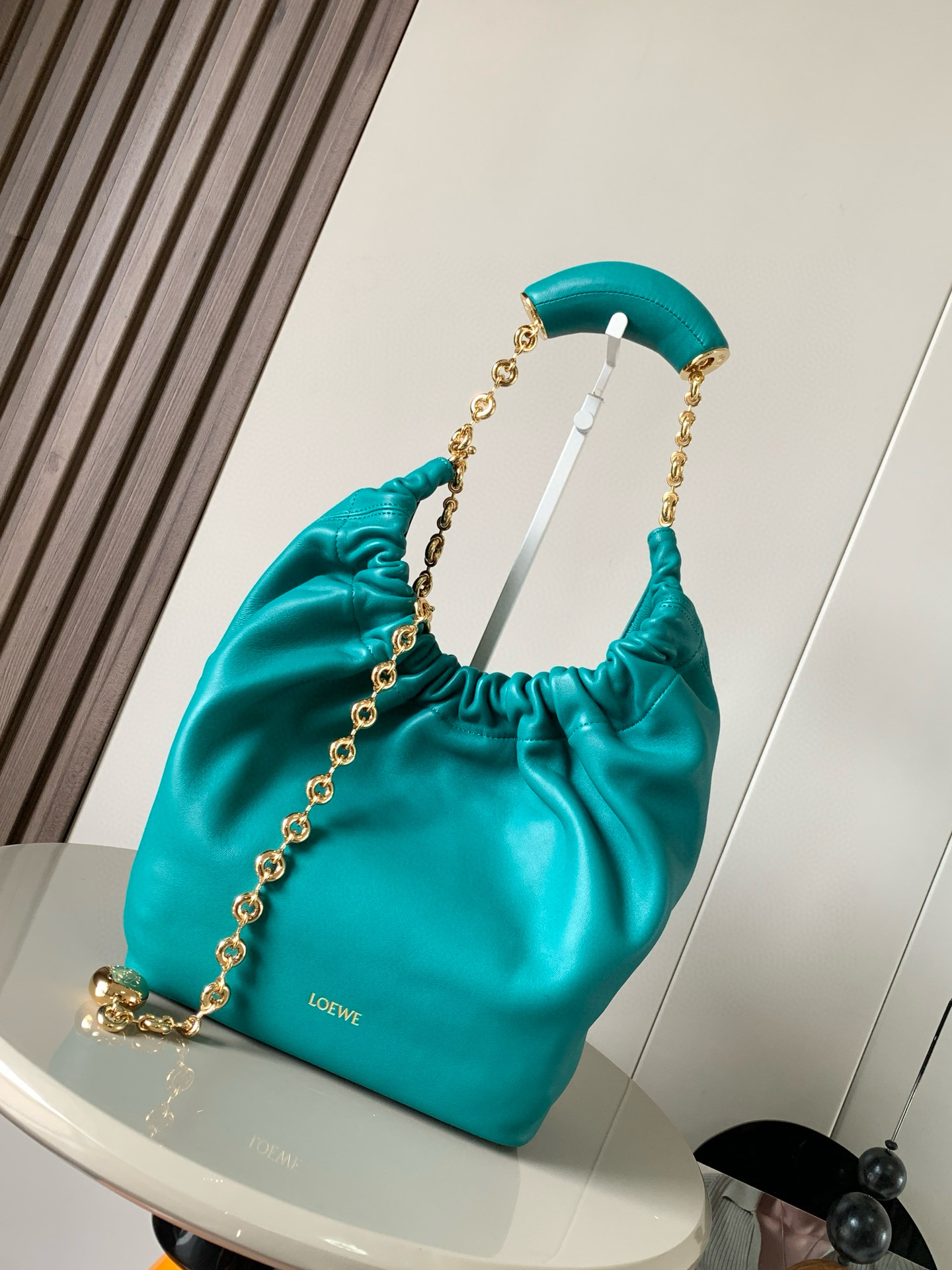 NO:209012,[Same Model in Celebrity] Small Napa Sheep Leather Squeeze Handbag is a new exquisite and soft handbag. The newly released Squeeze Handbag is made of soft and silky Mellow Napa Lambskin. The unlined structure effectively reduces the body's weight and is lighter. The meniscus shaped bag has an elegant ruffle closing, creating a relaxed and casual attitude. Another highlight of this bag is the ergonomic Squeeze airbag handle and exquisite donut chain made of brass. The length can be adjusted by chain ring or extended chain can be added, so that the airbag handles such as handcarrying, shoulders, crossbody, etc. can slide freely to improve comfort. The bottom of the chain is decorated with an Anagram Pebble pendant, adding agile details to the bag. Size 29CM~24CM~10.5CM  Model number 9042 Color Emerald Green, Loewe, sheepskin19860909【明星同款】小号纳帕羊皮革Squeeze手袋是款精致而柔美的全新手袋全新发布的 Squeeze 手袋采用柔软丝滑的Mellow纳帕小羊皮制作而成无衬里结构有效减轻包身自重观感上也更为轻盈弯月形包口以优雅的褶边收口,营造出轻松又随性的态度这款包包还有一大亮点是符合人体工程学的 Squeeze 气囊手柄搭配黄铜打造的精美甜甜圈链条可通过链环调节长短或添加延长链,实现手拎、肩背、斜挎等不同背法气囊手柄可自由滑动位置以提升舒适度链条底部点缀一枚 Anagram Pebble 吊坠,为包包增添灵动细节 尺寸29CM～24CM～10.5CM 款号9042 颜色翡翠绿,罗意威,loewe,sheepskin,Bag