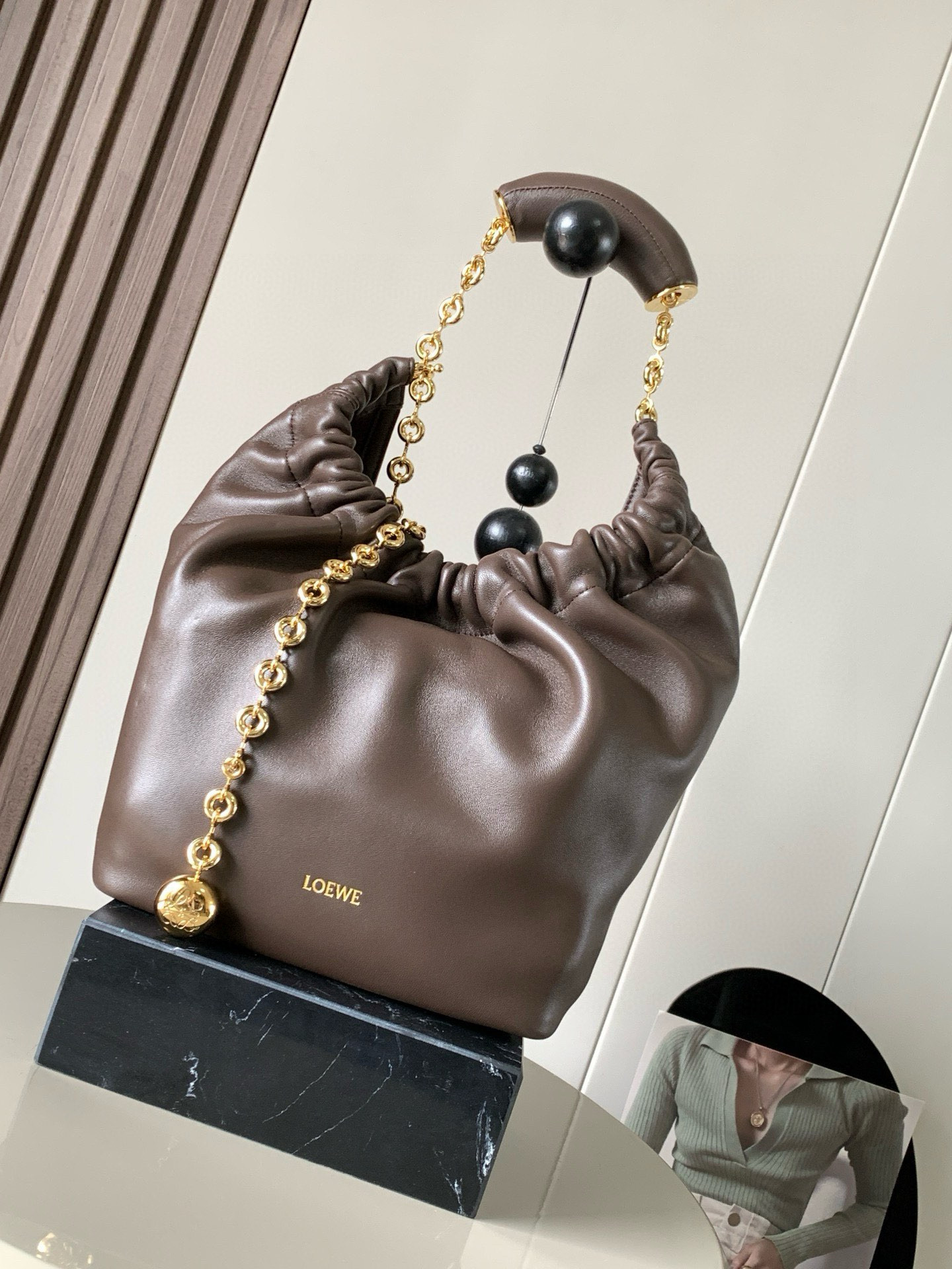 NO:209032,[Same Model in Celebrity] Small Napa Sheep Leather Squeeze Handbag is a new exquisite and soft handbag. The newly released Squeeze Handbag is made of soft and silky Mellow Napa Lambskin. The unlined structure effectively reduces the body's weight and is lighter. The meniscus shaped bag has an elegant ruffle closing, creating a relaxed and casual attitude. Another highlight of this bag is the ergonomic Squeeze airbag handle and exquisite donut chain made of brass. The length can be adjusted by chain ring or extended chain can be added, so that the airbag handles such as handcarrying, shoulders, crossbody, etc. can slide freely to improve comfort. The bottom of the chain is decorated with an Anagram Pebble pendant, adding agile details to the bag. Size 29CM~24CM~10.5CM  Model number 9042 Color chocolate, Loewe, sheepskin19860909【明星同款】小号纳帕羊皮革Squeeze手袋是款精致而柔美的全新手袋全新发布的 Squeeze 手袋采用柔软丝滑的Mellow纳帕小羊皮制作而成无衬里结构有效减轻包身自重观感上也更为轻盈弯月形包口以优雅的褶边收口,营造出轻松又随性的态度这款包包还有一大亮点是符合人体工程学的 Squeeze 气囊手柄搭配黄铜打造的精美甜甜圈链条可通过链环调节长短或添加延长链,实现手拎、肩背、斜挎等不同背法气囊手柄可自由滑动位置以提升舒适度链条底部点缀一枚 Anagram Pebble 吊坠,为包包增添灵动细节 尺寸29CM～24CM～10.5CM 款号9042 颜色巧克力,罗意威,loewe,sheepskin,Bag