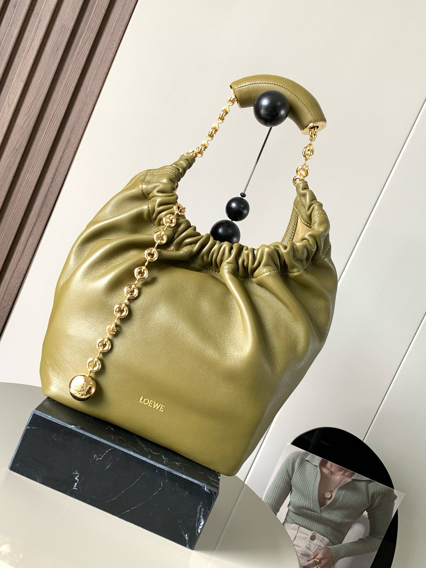 NO:209042,[Same Model in Celebrity] Small Napa Sheep Leather Squeeze Handbag is a new exquisite and soft handbag. The newly released Squeeze Handbag is made of soft and silky Mellow Napa Lambskin. The unlined structure effectively reduces the body's weight and is lighter. The meniscus shaped bag has an elegant ruffle closing, creating a relaxed and casual attitude. Another highlight of this bag is the ergonomic Squeeze airbag handle and exquisite donut chain made of brass. The length can be adjusted by chain ring or extended chain can be added, so that the airbag handles such as handcarrying, shoulders, crossbody, etc. can slide freely to improve comfort. The bottom of the chain is decorated with an Anagram Pebble pendant, adding agile details to the bag. Size 29CM~24CM~10.5CM  Olive green, Loewe, sheepskin19860909【明星同款】小号纳帕羊皮革Squeeze手袋是款精致而柔美的全新手袋全新发布的 Squeeze 手袋采用柔软丝滑的Mellow纳帕小羊皮制作而成无衬里结构有效减轻包身自重观感上也更为轻盈弯月形包口以优雅的褶边收口,营造出轻松又随性的态度这款包包还有一大亮点是符合人体工程学的 Squeeze 气囊手柄搭配黄铜打造的精美甜甜圈链条可通过链环调节长短或添加延长链,实现手拎、肩背、斜挎等不同背法气囊手柄可自由滑动位置以提升舒适度链条底部点缀一枚 Anagram Pebble 吊坠,为包包增添灵动细节 尺寸29CM～24CM～10.5CM 款号橄榄绿,罗意威,loewe,sheepskin,Bag