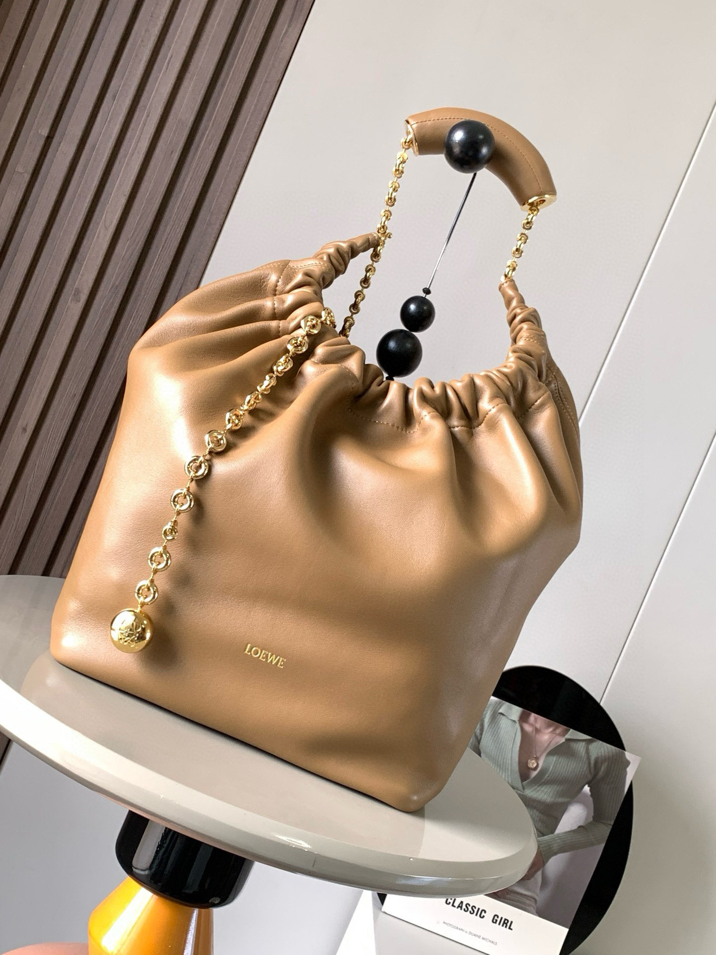 NO:209317,【Same Model for Celebrity】The medium-sized Napa Sheep Leather Squeeze handbag is a new exquisite and soft handbag. The newly released Squeeze handbag is made of soft and silky Mellow Napa Lambskin, which effectively reduces the weight of the bag. It is also lighter. The meniscus shaped bag has an elegant ruffle closing, creating a relaxed and casual attitude. Another highlight of this bag is that the ergonomic Squeeze airbag handle is matched with exquisite donut chains made of brass. The length can be adjusted by chain rings or extended chains can be added, so that the airbag handles such as handcarrying, shoulders, crossbody, etc. can slide freely to improve comfort. The bottom of the chain is decorated with an Anagram Pebble pendant, adding agile details to the bag. Size 34CM~33CM~13.5CM  Model number 9041 Color oak brown, Loewe, sheepskin19860909【明星同款】中号纳帕羊皮革Squeeze手袋是款精致而柔美的全新手袋全新发布的 Squeeze 手袋采用柔软丝滑的Mellow纳帕小羊皮制作而成无衬里结构有效减轻包身自重观感上也更为轻盈弯月形包口以优雅的褶边收口,营造出轻松又随性的态度这款包包还有一大亮点是符合人体工程学的 Squeeze 气囊手柄搭配黄铜打造的精美甜甜圈链条可通过链环调节长短或添加延长链,实现手拎、肩背、斜挎等不同背法气囊手柄可自由滑动位置以提升舒适度链条底部点缀一枚 Anagram Pebble 吊坠,为包包增添灵动细节 尺寸34CM～33CM～13.5CM 款号9041 颜色橡木棕,罗意威,loewe,sheepskin,Bag