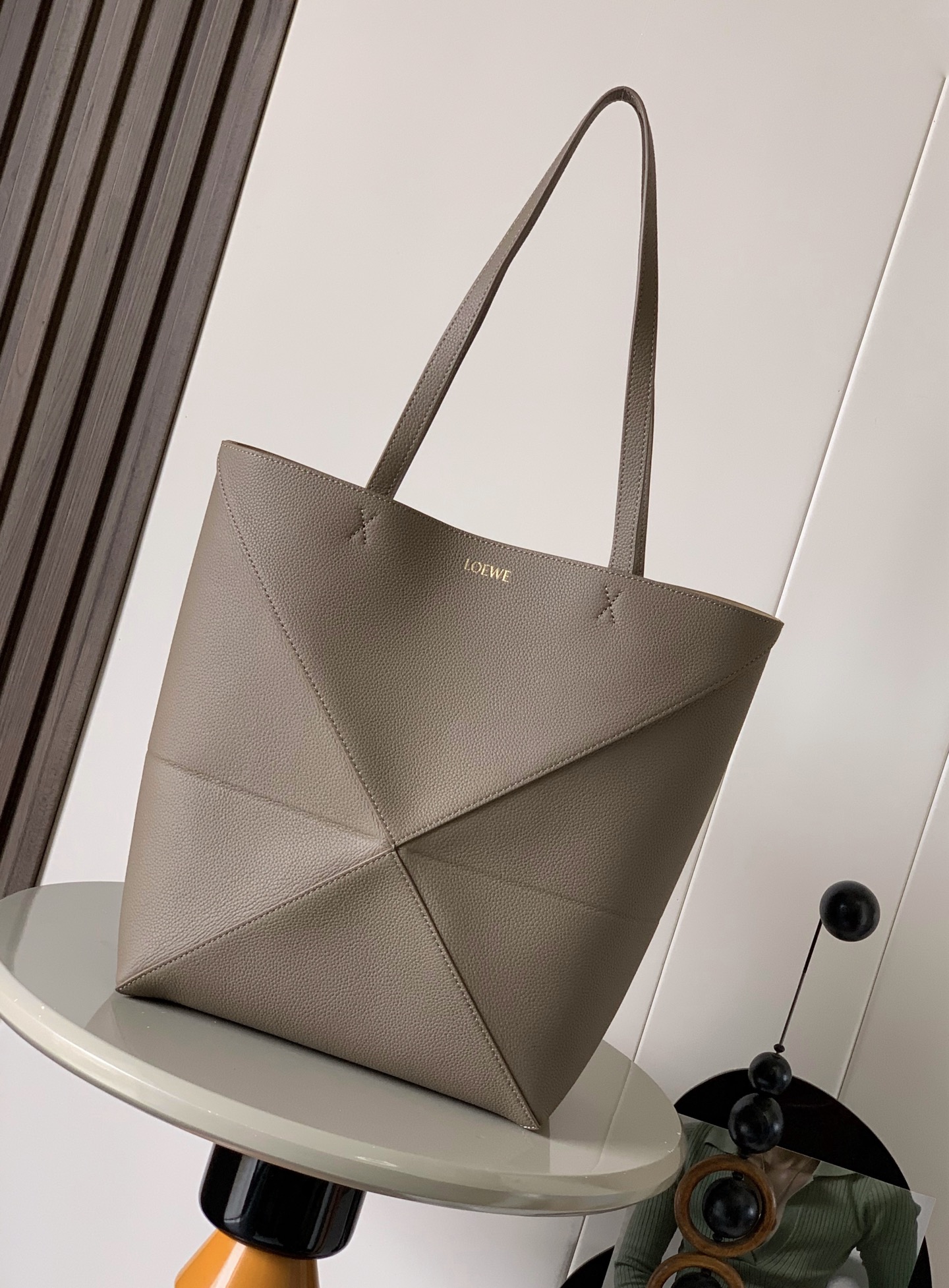 NO:388485,The new lyifang cowhide leather puzzle Fold handbag has played the geometric shapes for a long time. It has not been seen such a practical and full of design. This tote bag continues the geometric aesthetics of the Puzzle series, inspired by origami bags, allowing this Puzzle Fold tote to switch the upper body in three-dimensional and flat surfaces. Two sizes are for reference. Large size is more friendly in capacity, small size is cute, the leather is very delicate and the weight is super light, and it can be folded and is suitable for commuting with computers, or for daily business trips, like me, to store and store for trunks. Puzzle Fold handbag draws inspiration from the geometric lines of the brand's classic handbag series with creativity and ingenuity to reinterpret it into a fashionable tote bag. It can be completely folded and is a good companion for traveling. This medium version is made of soft shiny cowhide leather.  Size 31~25~14CM Model number 9029 Color gray-brown lyre, Luo Yiwei, loewe, totes, cowhide19860909新款荔面牛皮革puzzle Fold手袋又把几何图形玩出花了很久没见过这么实用又设计感满满的托特包了这款延续了Puzzle系列的几何美学以折纸包为灵感,让这只 Puzzle Fold tote 在立体和平面随意切换上身了两个尺码给大家参考哦大号容量更友好,小号很可爱,皮质都很细腻光泽本身自重超轻,外加可以折叠太适合平时带电脑通勤,或是像我一样经常出差旅行不费力的收纳进行李箱,Puzzle Fold手袋从品牌经典手袋系列的几何线条汲取灵感运用创意巧思将其重新诠释为一款时尚的托特袋,能完全折叠是旅行良伴.这个中号版本采用柔软的亮面牛皮革打造 尺寸31～25～14CM 款号9029 颜色灰褐色荔,罗意威,loewe,totes,cowhide,Bag