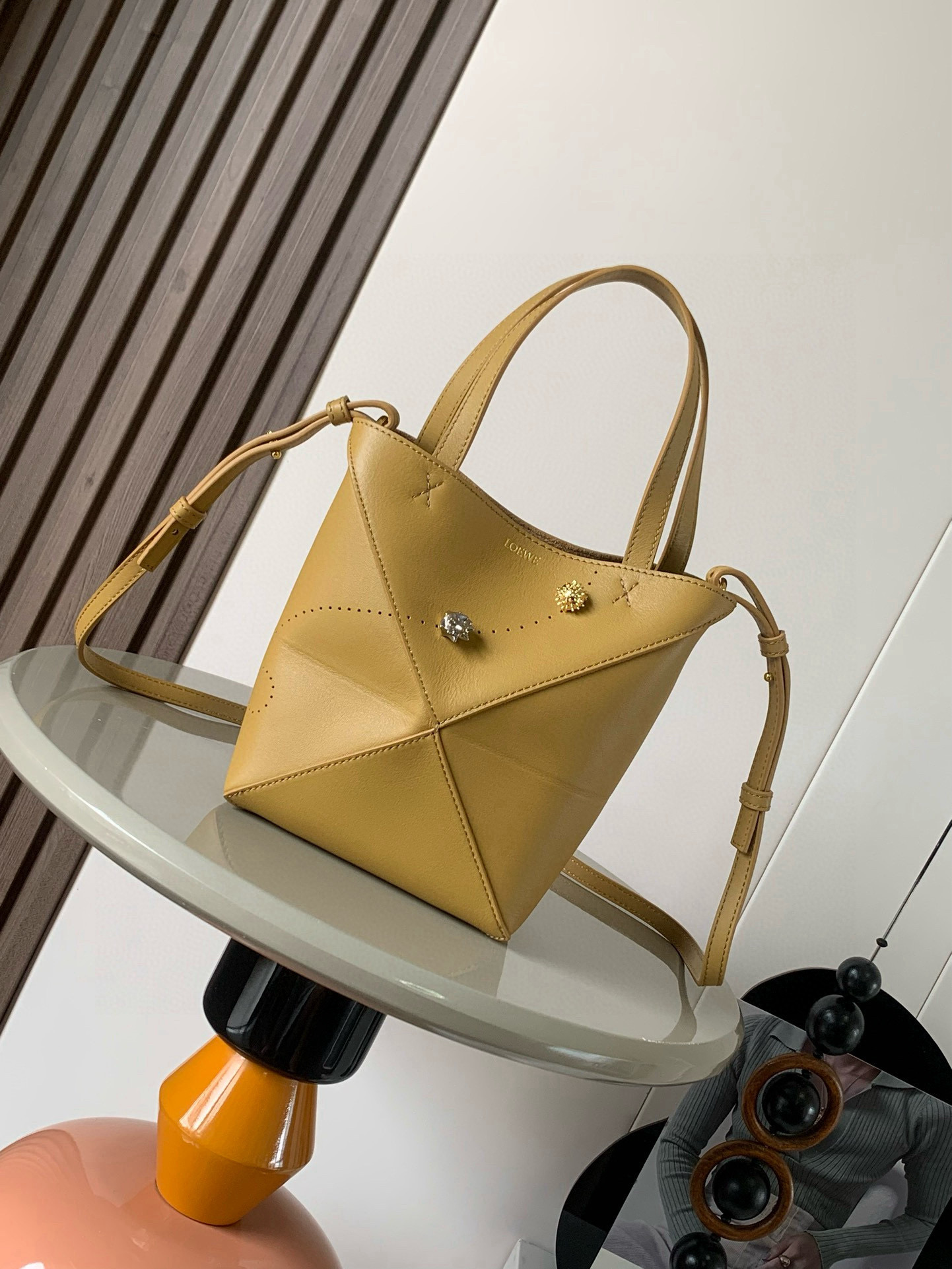 NO:394907,Mini glossy cowhide leather Puzzle Fold Handbag New Puzzle Fold Handbag is a soft and lightweight design inspired by the iconic handbag. The geometric lines have been reinterpreted, exquisitely presenting geometric inserts that can be completely flat folded and structured. This mini version is made of glossy cowhide leather, and the perforated presents two special edition hedgehog pins that can be removed and repositioned along the punching holes. * Can be shoulder-mounted, cross-body or hand-held * Removable and adjustable shoulder straps * Suede lining * Gold stamping LOEWE Size 16.5cm~9.5cm~20cm Model No. 9030A Color Warm Sand Yellow, Loewe, loewe, loewe, cowhide19860909迷你亮面牛皮革 PuzzleFold手袋新品Puzzle Fold 手袋采用柔软而轻盈的设计灵感来自标志性手袋其几何线条经过重新诠释,精巧呈现能够完全扁平折叠、结构化的几何镶片.此迷你版本采用亮面牛皮革制成,穿孔呈现两个可以沿着打孔拆卸和重新定位的特别版刺猬别针.＊可肩背、斜挎或手提＊可拆卸和可调节肩带＊绒面革衬里＊烫金 LOEWE 尺寸16.5cm～9.5cm～20 cm 款号9030A 颜色暖沙黄,罗意威,loewe,loewe,cowhide,Bag