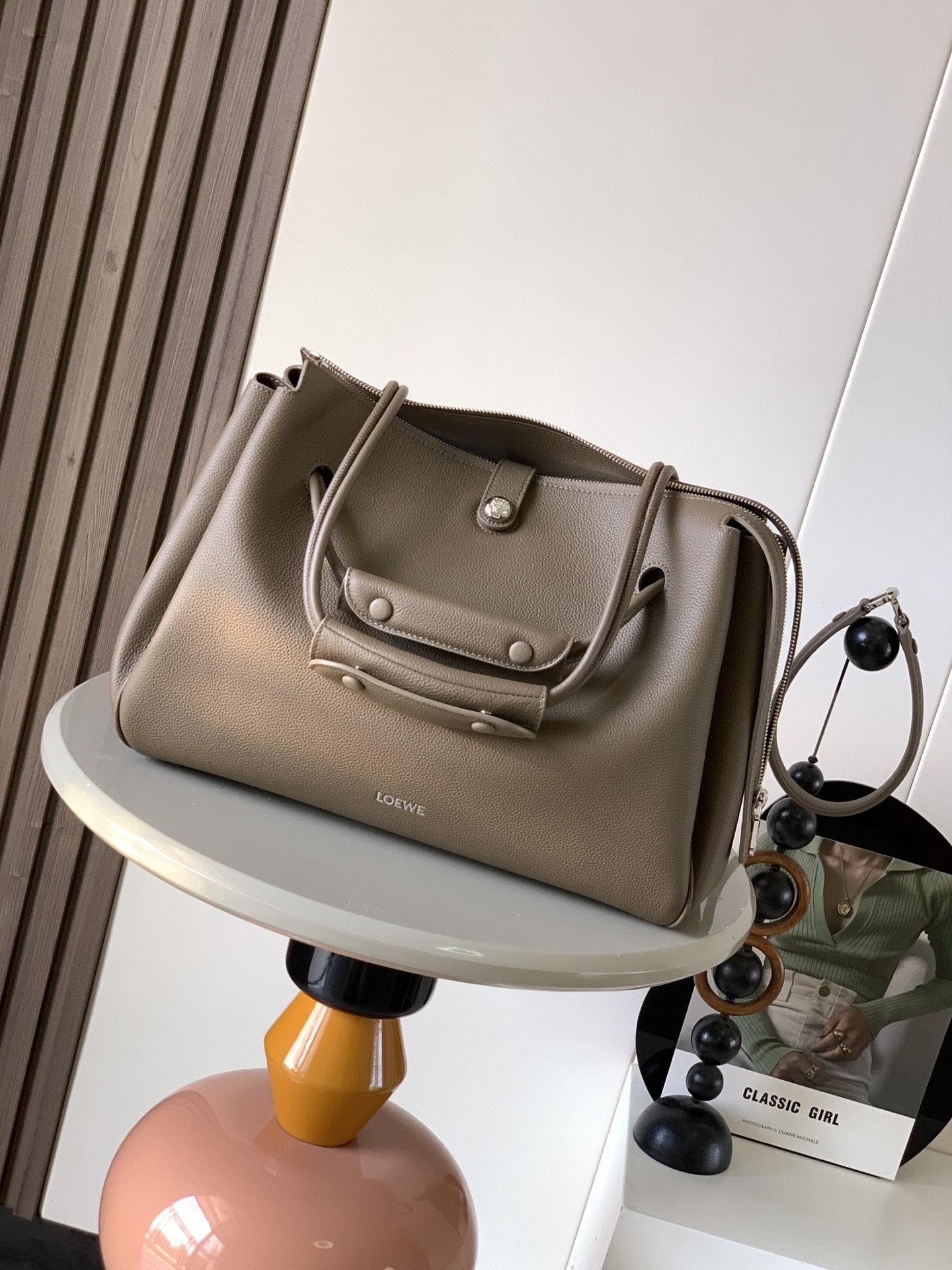 NO:394938,Large soft cowhide leather Madrid handbags Madrid has a soft structure and a trapezoidal shape with an adjustable handle and a Pebble magnetic buckle This large version is made of soft cowhide leather with a shoulder-back, crossbody or hand-held* adjustable shoulder straps, paired with leather extension straps *AnagramPebble magnetic buckle zipper closure *One zipper inner bag *Anagram Pebble metal foot nails *Napa sheepskin lining Size 33CM~24CM~12.5CM Model No. 9148 Color Taupe, Loewe, cowhide, sheepskin19860909大号柔软牛皮革 Madrid手袋Madrid 具有柔软的结构感梯形造型采用角撑设计,搭配可调节提手和 Pebble 磁扣此大号版本采用柔软牛皮革制成*可肩背、斜挎或手提*可调节肩带,搭配皮革延长带 *AnagramPebble 磁扣开合拉链开合*一个拉链内袋 *Anagram Pebble金属脚钉*纳帕羊皮革衬里 尺寸33CM～24CM～12.5CM 款号9148 颜色灰褐色荔,罗意威,loewe,cowhide,sheepskin,Bag