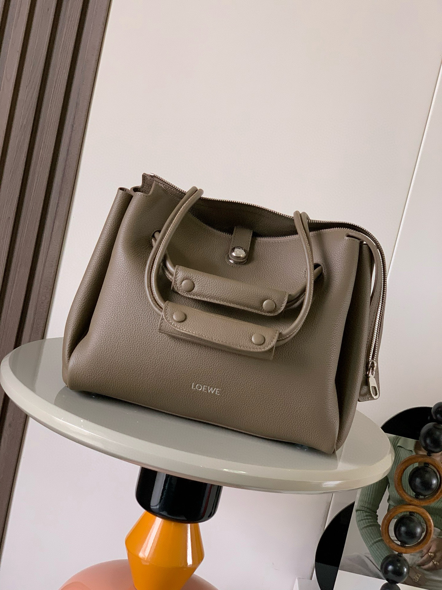 NO:406419,Medium soft cowhide leather Madrid handbags Madrid has a soft structure and a trapezoidal shape with an adjustable handle and a Pebble magnetic buckle This medium version is made of soft cowhide leather with a shoulder-back, crossbody or hand-held* adjustable shoulder straps, paired with leather extension straps *AnagramPebble magnetic buckle zipper closure*One zipper inner bag *Anagram Pebble metal foot nails*Napa sheepskin lining Size 28.5CM~23CM~11CM Model No. 9147 Color Taupe, Loewe, cowhide, sheepskin19860909中号柔软牛皮革 Madrid手袋Madrid 具有柔软的结构感梯形造型采用角撑设计,搭配可调节提手和 Pebble 磁扣此中号版本采用柔软牛皮革制成*可肩背、斜挎或手提*可调节肩带,搭配皮革延长带 *AnagramPebble 磁扣开合拉链开合*一个拉链内袋 *Anagram Pebble金属脚钉*纳帕羊皮革衬里 尺寸28.5CM～23CM～11CM 款号9147 颜色灰褐色荔,罗意威,loewe,cowhide,sheepskin,Bag