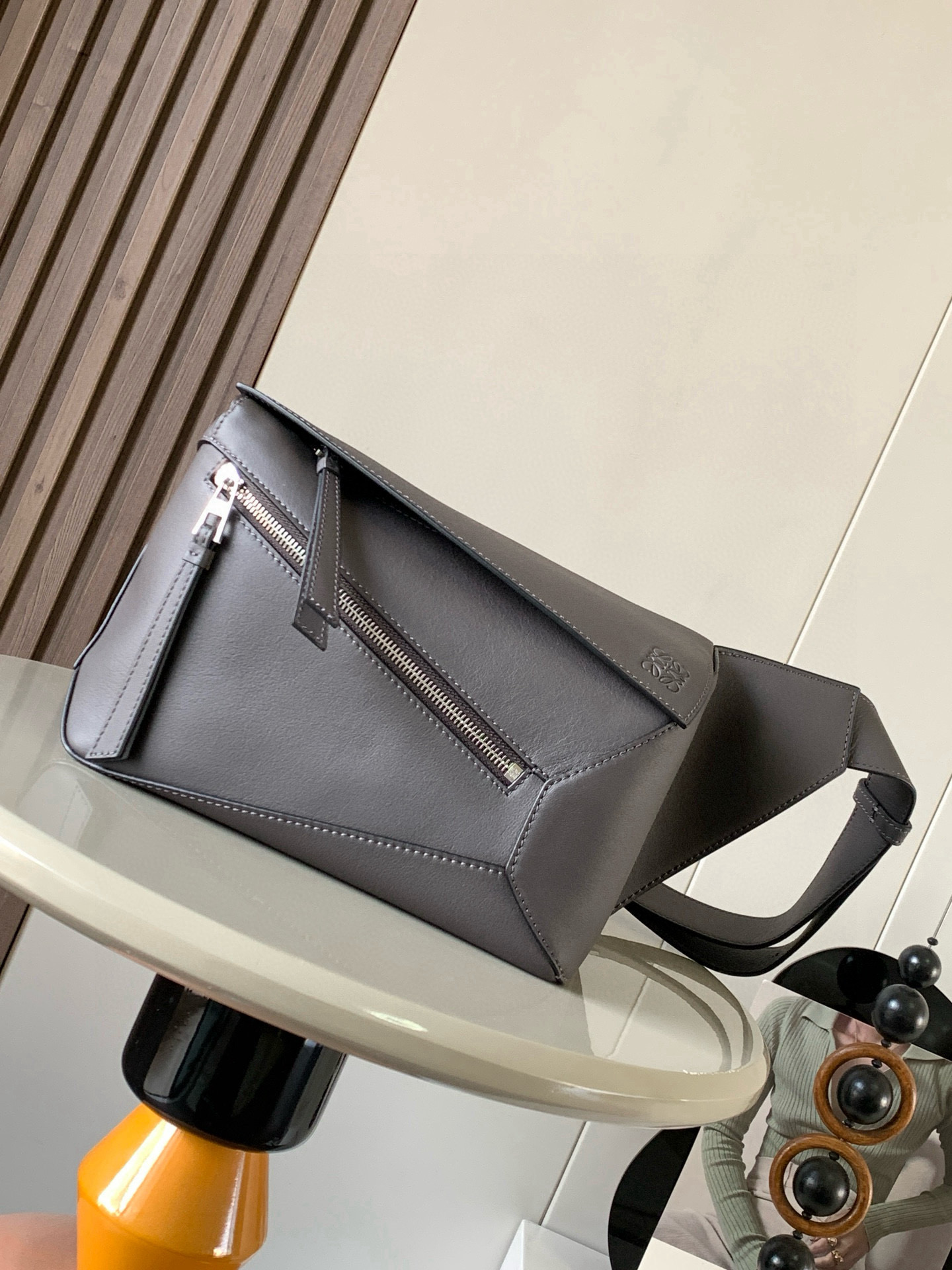 NO:532703,The new small classic cowhide leather Puzzle waist bag rectangular shape and precise cutting technology create Puzzle's unique geometric lines. This small waist bag is made of classic cowhide leather. It is soft and light. It has a low-key and recognizable shape. It can be matched with both business and casual. Later, I found a puzzle waist bag. Compared with classic, Puzzle is relatively niche. This waist bag removes the handle of the classic puzzle. The rear zipper bag at the back of the classic puzzle is moved to the front belt and becomes an unremovable latch buckle wide belt retains the basic bag shape of the classic puzzle casual literary style. In addition, the fork adds a cool mechanical feel and is also classic and versatile. Not only is the capacity considerable, but the upper body proportions are better. Shoulder or crossbody, adjustable shoulder straps, and metal buckle closure.  Size 24CM~16CM~10.5CM Model number 9114 Color gray brown, Loewe, cowhide19860909新款小号经典牛皮革 Puzzle 腰包长方体形状和精确的切割技术创造了Puzzle 独特的几何线条这款小号腰包采用经典牛皮革制成皮质柔软轻便,造型低调有辨识度不管是商务还是休闲都可以搭配后来叉发现一款 puzzle腰包,相对经典,puzzle 来说比较小众此款腰包去掉了经典puzzle的手柄把经典puzzle 后面的后置拉链袋移到了前面腰带也变成不可拆卸插销扣宽腰带保留经典puzzle随性文艺的基本包型外,叉增加了一份酷酷的机械感同样经典百搭. 不仅容量可观而且上身比例更好.肩背或斜挎 ,可调节肩带,配有金属搭扣开合 尺寸24CM～16CM～10.5CM 款号9114 颜色灰咖色,罗意威,loewe,cowhide,Bag