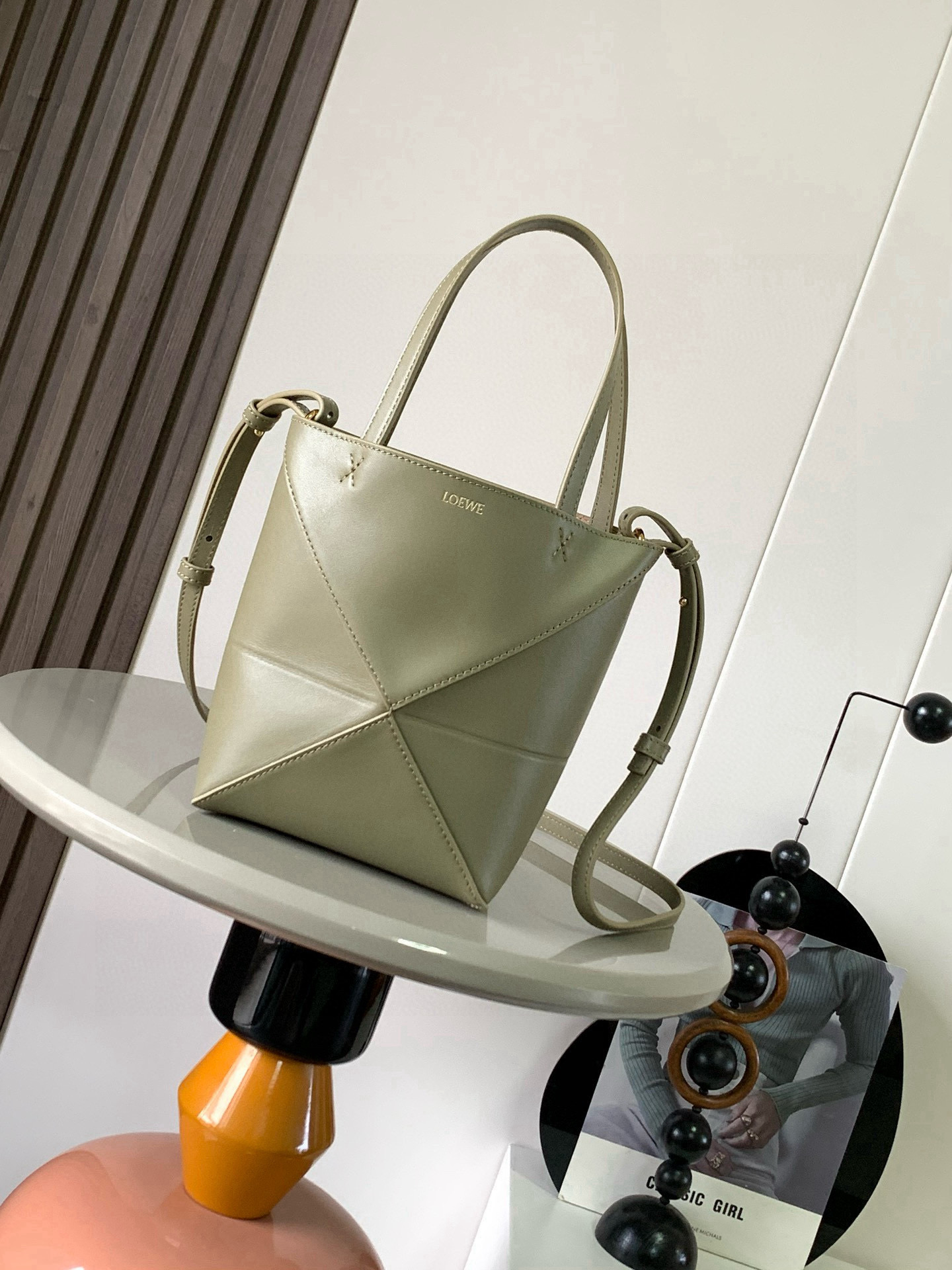 NO:556363,The new glossy cow leather mini puzzle Fold handbag plays with geometric patterns again. It has been a long time since I have seen such a practical and design tote bag. This one continues the geometric aesthetics of the Puzzle series. Inspired by the origami bag, this Puzzle Fold tote can switch between three-dimensional and flat surfaces at will. The leather is very delicate and shiny. It is ultra-light in weight, and the Puzzle can be folded.  The Fold handbag draws inspiration from the geometric lines of the brand's classic handbag series and uses creative ingenuity to reinterpret it into a fashionable tote bag that can be completely folded and is a good travel companion. This mini version is made of soft glossy cowhide. Size 20CM～16.5CM～9CM. Style No. 9030. Color: eucalyptus green, Loewe, loewe, totes, cowhide.19860909新款亮面牛皮革迷你号puzzle Fold手袋又把几何图形玩出花了很久没见过这么实用又设计感满满的托特包了这款延续了Puzzle系列的几何美学以折纸包为灵感,让这只 Puzzle Fold tote 在立体和平面随意切换皮质都很细腻光泽本身自重超轻,外加可以折叠Puzzle Fold手袋从品牌经典手袋系列的几何线条汲取灵感运用创意巧思将其重新诠释为一款时尚的托特袋,能完全折叠是旅行良伴.这个迷你号版本采用柔软的亮面牛皮革打造 尺寸20CM～16.5CM～9CM 款号9030 颜色桉树绿,罗意威,loewe,totes,cowhide,Bag