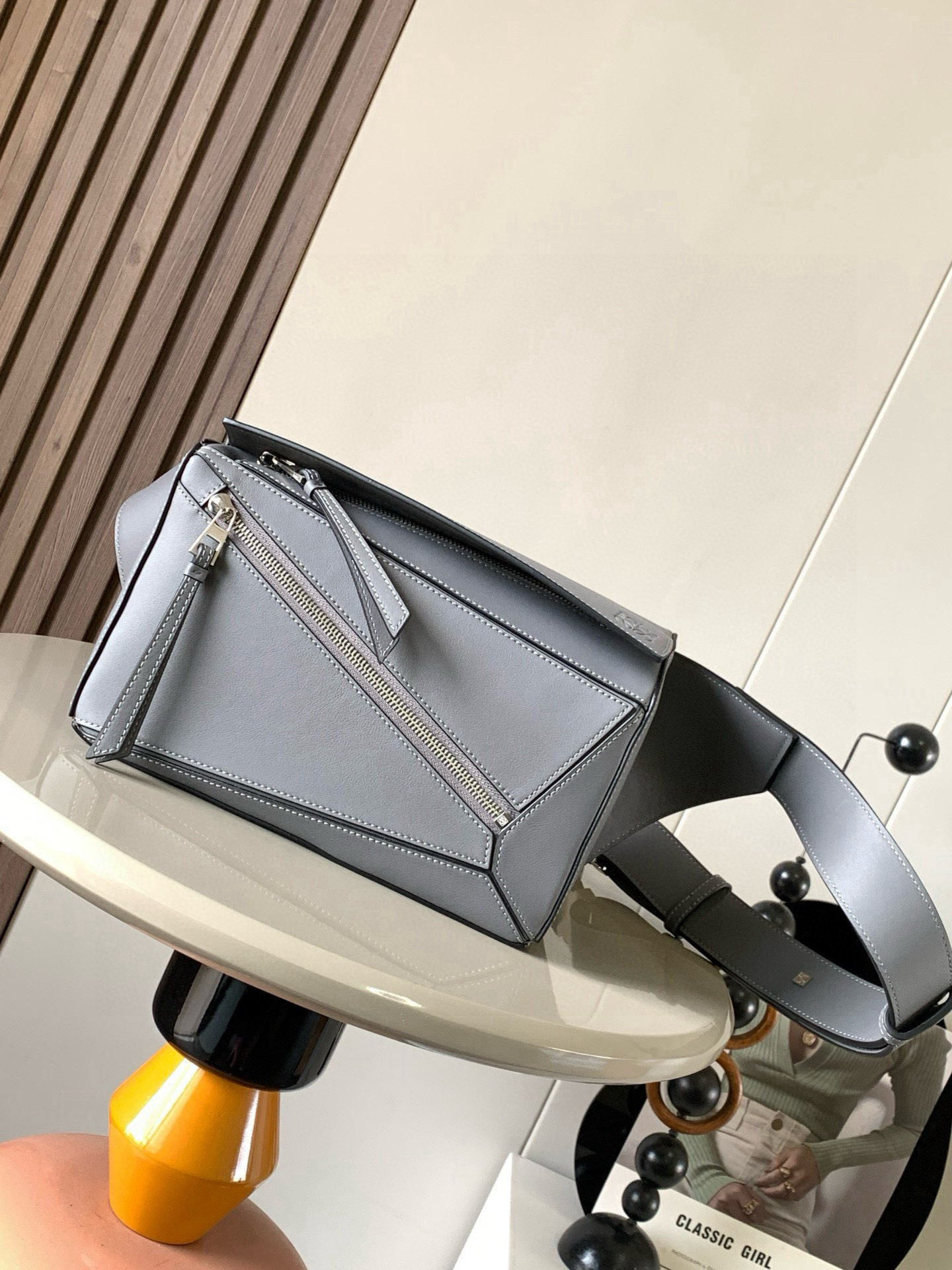 NO:582149,Small classic cow leather Puzzle waist bag The rectangular shape and precise cutting technology create Puzzle's unique geometric lines. This small waist bag is made of classic cow leather. The leather is soft and lightweight, and the shape is low-key and recognizable. It can be matched with the back for both business and leisure. I found a puzzle waist bag, which is relatively classic and relatively niche for puzzle. This waist bag removes the handle of the classic puzzle and puts the classic puzzle  The rear zipper bag has been moved to the front belt and has become a non-detachable latch buckle wide belt. In addition to retaining the classic puzzle casual and artistic basic bag shape, the fork adds a cool mechanical feel and is also classic and versatile. It not only has considerable capacity but also has a better upper body proportion. Shoulder or crossbody, adjustable shoulder strap, equipped with metal buckle closure. Size 24CM～16CM～10.5CM. Style No. 8014. Color gray, Loewe, loewe, cowhide.19860909小号经典牛皮革 Puzzle 腰包长方体形状和精确的切割技术创造了Puzzle 独特的几何线条这款小号腰包采用经典牛皮革制成皮质柔软轻便,造型低调有辨识度不管是商务还是休闲都可以搭配后来叉发现一款 puzzle腰包,相对经典,puzzle 来说比较小众此款腰包去掉了经典puzzle的手柄把经典puzzle 后面的后置拉链袋移到了前面腰带也变成不可拆卸插销扣宽腰带保留经典puzzle随性文艺的基本包型外,叉增加了一份酷酷的机械感同样经典百搭. 不仅容量可观而且上身比例更好.肩背或斜挎 ,可调节肩带,配有金属搭扣开合 尺寸24CM～16CM～10.5CM 款号8014 颜色灰色,罗意威,loewe,cowhide,Bag