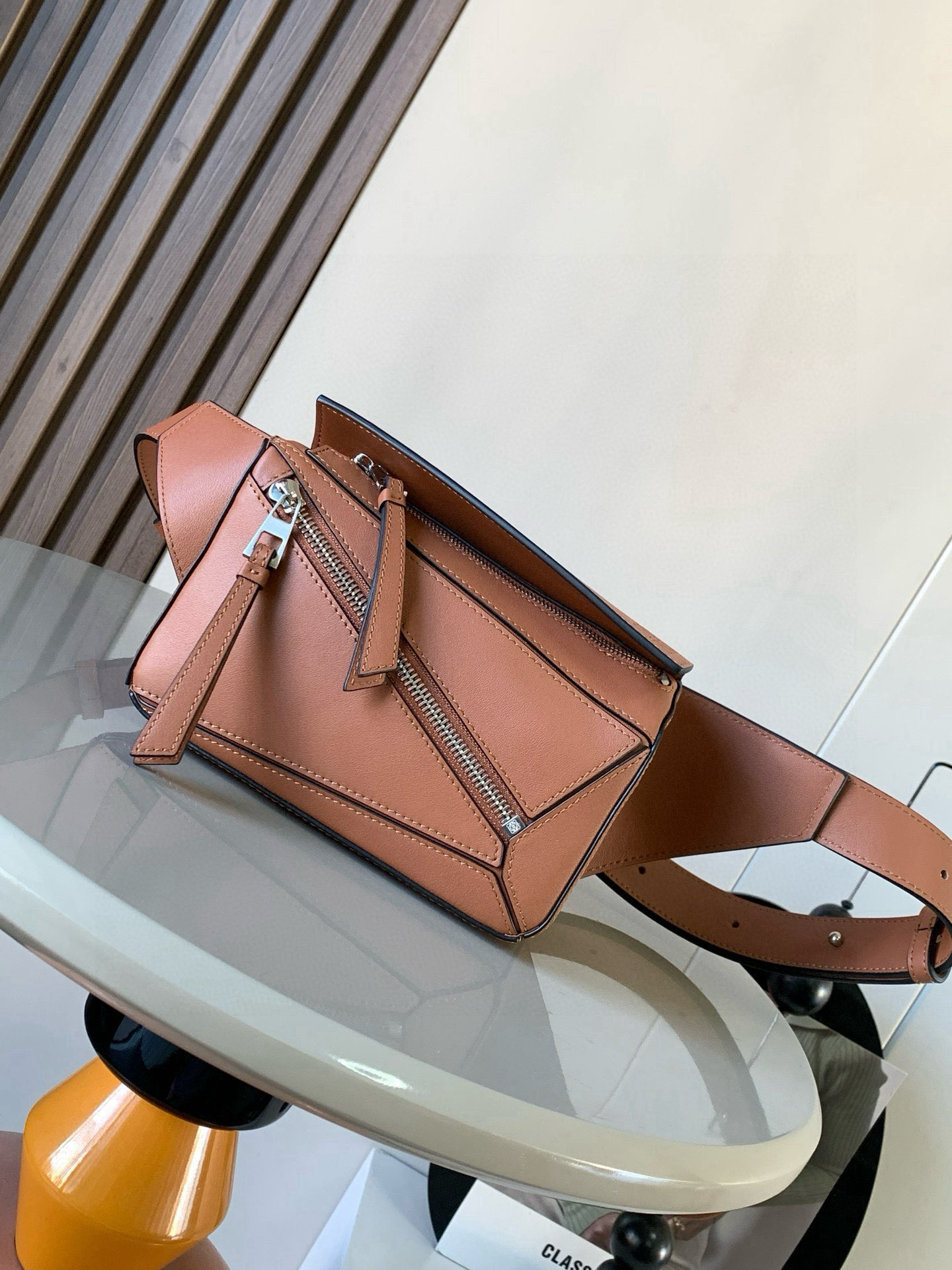 NO:582156,The mini classic cow leather Puzzle waist bag’s rectangular shape and precise cutting technology create Puzzle’s unique geometric lines. This small mini waist bag is made of classic cow leather. The leather is soft and lightweight, and the shape is low-key and recognizable. It can be worn with it whether it is for business or leisure. I found a puzzle waist bag, which is relatively classic and relatively niche for puzzle. This waist bag removes the handle of the classic puzzle and turns the classic puzzle  The rear rear zipper bag has been moved to the front belt and has become a non-detachable latch buckle wide belt. In addition to retaining the classic puzzle casual and literary basic bag shape, the fork adds a cool mechanical feel and is also classic and versatile. Not only is the capacity considerable, but the upper body proportion is better. Shoulder or crossbody, adjustable shoulder strap, equipped with metal buckle opening and closing. Size 18CM～12CM～7.5CM. Style No. 8013. Color brown, Loewe, loewe, cowhide.19860909迷你号经典牛皮革 Puzzle 腰包长方体形状和精确的切割技术创造了Puzzle 独特的几何线条这款小迷你号腰包采用经典牛皮革制成皮质柔软轻便,造型低调有辨识度不管是商务还是休闲都可以搭配后来叉发现一款 puzzle腰包,相对经典,puzzle 来说比较小众此款腰包去掉了经典puzzle的手柄把经典puzzle 后面的后置拉链袋移到了前面腰带也变成不可拆卸插销扣宽腰带保留经典puzzle随性文艺的基本包型外,叉增加了一份酷酷的机械感同样经典百搭.不仅容量可观而且上身比例更好.肩背或斜挎 ,可调节肩带,配有金属搭扣开合 尺寸18CM～12CM～7.5CM 款号8013 颜色棕色,罗意威,loewe,cowhide,Bag