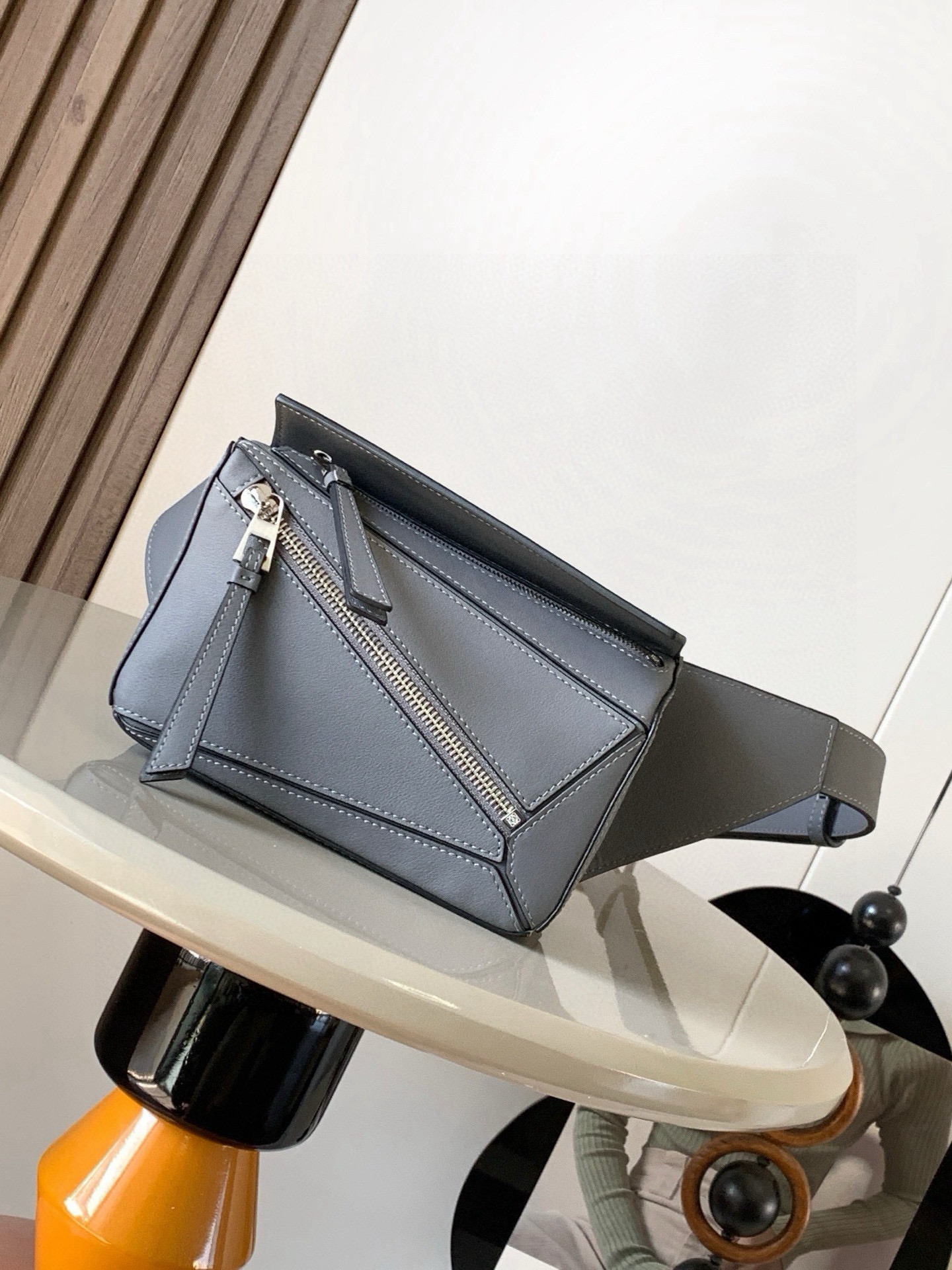 NO:574921,The mini classic cow leather Puzzle waist bag’s rectangular shape and precise cutting technology create Puzzle’s unique geometric lines. This small mini waist bag is made of classic cow leather. The leather is soft and lightweight, and the shape is low-key and recognizable. It can be worn with it whether it is for business or leisure. I found a puzzle waist bag, which is relatively classic and relatively niche for puzzle. This waist bag removes the handle of the classic puzzle and turns the classic puzzle  The rear zipper bag has been moved to the front belt and has become a non-detachable latch buckle wide belt. In addition to retaining the classic puzzle casual and artistic basic bag shape, the fork adds a cool mechanical feel and is also classic and versatile. Not only is the capacity considerable, but the upper body proportion is better. Shoulder or cross-body, adjustable shoulder strap, equipped with metal buckle closure. Size 18CM～12CM～7.5CM. Style No. 8013. Color gray, Loewe, cowhide.19860909迷你号经典牛皮革 Puzzle 腰包长方体形状和精确的切割技术创造了Puzzle 独特的几何线条这款小迷你号腰包采用经典牛皮革制成皮质柔软轻便,造型低调有辨识度不管是商务还是休闲都可以搭配后来叉发现一款 puzzle腰包,相对经典,puzzle 来说比较小众此款腰包去掉了经典puzzle的手柄把经典puzzle 后面的后置拉链袋移到了前面腰带也变成不可拆卸插销扣宽腰带保留经典puzzle随性文艺的基本包型外,叉增加了一份酷酷的机械感同样经典百搭.不仅容量可观而且上身比例更好.肩背或斜挎 ,可调节肩带,配有金属搭扣开合 尺寸18CM～12CM～7.5CM 款号8013 颜色灰色,罗意威,loewe,cowhide,Bag