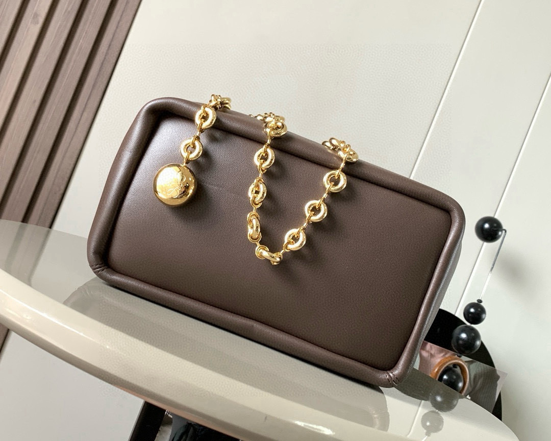 p980。🔥【明星同款】小号纳帕羊皮革Squeeze手袋💄是款精致而柔美的全新手袋💥全新发布的 Squeeze 手袋采用柔软丝滑的Mellow纳帕小羊皮制作而成❤️无衬里结构有效减轻包身自重🌺观感上也更为轻盈⭐️弯月形包口以优雅的褶边收口，营造出轻松又随性的态度👜这款包包还有一大亮点是符合人体工程学的 Squeeze 气囊手柄🌼搭配黄铜打造的精美甜甜圈链条😘可通过链环调节长短或添加延长链，实现手拎、肩背、斜挎等不同背法😻气囊手柄可自由滑动位置以提升舒适度🌻链条底部点缀一枚 Anagram Pebble 吊坠，为包包增添灵动细节⚡️
尺寸：29CM～24CM～10.5CM
款号：9042
颜色：巧克力