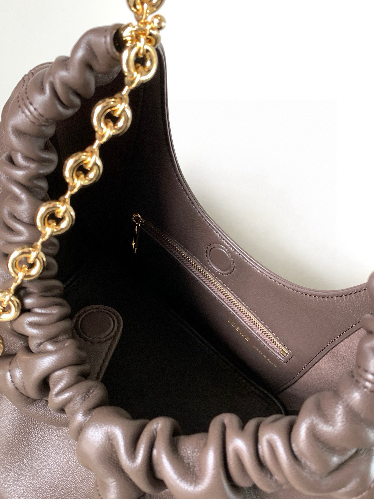 p980。🔥【明星同款】小号纳帕羊皮革Squeeze手袋💄是款精致而柔美的全新手袋💥全新发布的 Squeeze 手袋采用柔软丝滑的Mellow纳帕小羊皮制作而成❤️无衬里结构有效减轻包身自重🌺观感上也更为轻盈⭐️弯月形包口以优雅的褶边收口，营造出轻松又随性的态度👜这款包包还有一大亮点是符合人体工程学的 Squeeze 气囊手柄🌼搭配黄铜打造的精美甜甜圈链条😘可通过链环调节长短或添加延长链，实现手拎、肩背、斜挎等不同背法😻气囊手柄可自由滑动位置以提升舒适度🌻链条底部点缀一枚 Anagram Pebble 吊坠，为包包增添灵动细节⚡️
尺寸：29CM～24CM～10.5CM
款号：9042
颜色：巧克力