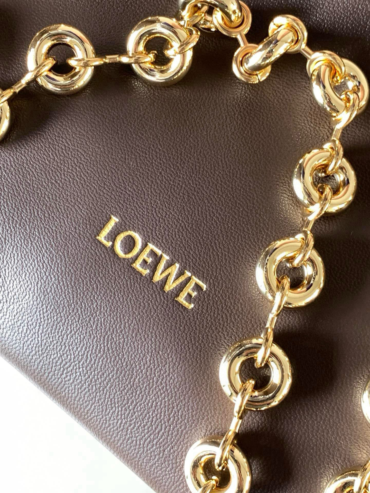 p980。🔥【明星同款】小号纳帕羊皮革Squeeze手袋💄是款精致而柔美的全新手袋💥全新发布的 Squeeze 手袋采用柔软丝滑的Mellow纳帕小羊皮制作而成❤️无衬里结构有效减轻包身自重🌺观感上也更为轻盈⭐️弯月形包口以优雅的褶边收口，营造出轻松又随性的态度👜这款包包还有一大亮点是符合人体工程学的 Squeeze 气囊手柄🌼搭配黄铜打造的精美甜甜圈链条😘可通过链环调节长短或添加延长链，实现手拎、肩背、斜挎等不同背法😻气囊手柄可自由滑动位置以提升舒适度🌻链条底部点缀一枚 Anagram Pebble 吊坠，为包包增添灵动细节⚡️
尺寸：29CM～24CM～10.5CM
款号：9042
颜色：巧克力