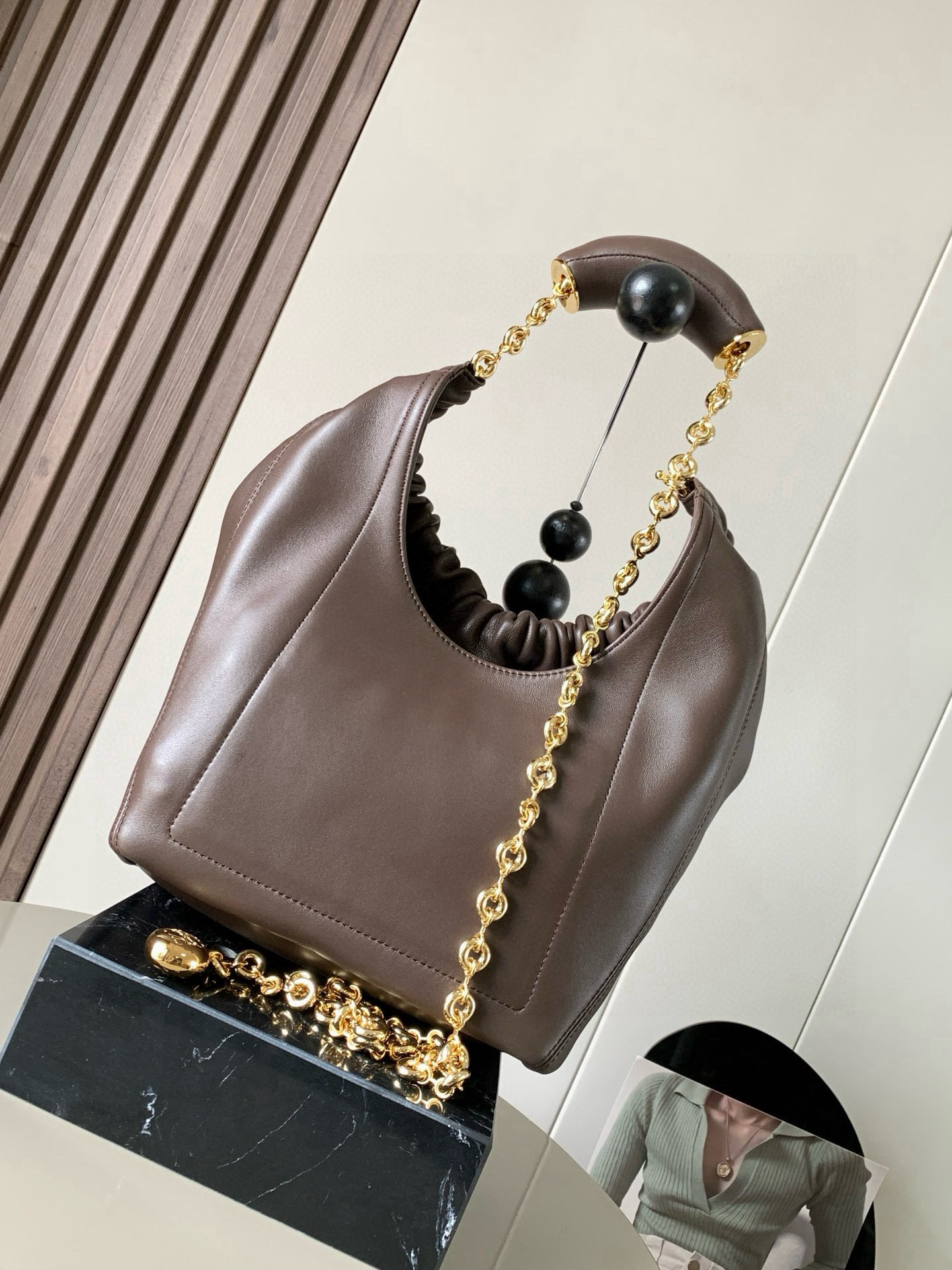 p980。🔥【明星同款】小号纳帕羊皮革Squeeze手袋💄是款精致而柔美的全新手袋💥全新发布的 Squeeze 手袋采用柔软丝滑的Mellow纳帕小羊皮制作而成❤️无衬里结构有效减轻包身自重🌺观感上也更为轻盈⭐️弯月形包口以优雅的褶边收口，营造出轻松又随性的态度👜这款包包还有一大亮点是符合人体工程学的 Squeeze 气囊手柄🌼搭配黄铜打造的精美甜甜圈链条😘可通过链环调节长短或添加延长链，实现手拎、肩背、斜挎等不同背法😻气囊手柄可自由滑动位置以提升舒适度🌻链条底部点缀一枚 Anagram Pebble 吊坠，为包包增添灵动细节⚡️
尺寸：29CM～24CM～10.5CM
款号：9042
颜色：巧克力