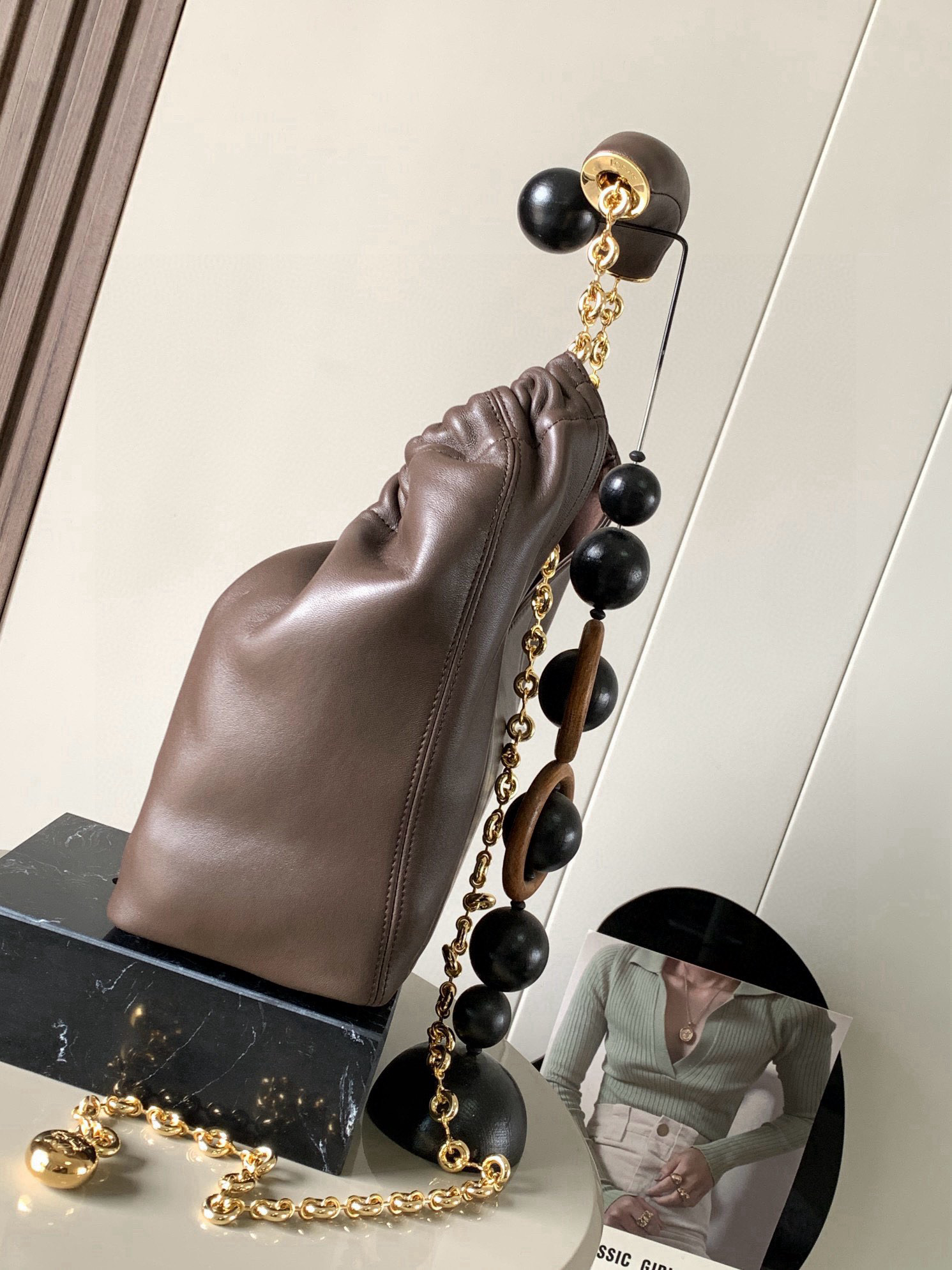 p980。🔥【明星同款】小号纳帕羊皮革Squeeze手袋💄是款精致而柔美的全新手袋💥全新发布的 Squeeze 手袋采用柔软丝滑的Mellow纳帕小羊皮制作而成❤️无衬里结构有效减轻包身自重🌺观感上也更为轻盈⭐️弯月形包口以优雅的褶边收口，营造出轻松又随性的态度👜这款包包还有一大亮点是符合人体工程学的 Squeeze 气囊手柄🌼搭配黄铜打造的精美甜甜圈链条😘可通过链环调节长短或添加延长链，实现手拎、肩背、斜挎等不同背法😻气囊手柄可自由滑动位置以提升舒适度🌻链条底部点缀一枚 Anagram Pebble 吊坠，为包包增添灵动细节⚡️
尺寸：29CM～24CM～10.5CM
款号：9042
颜色：巧克力