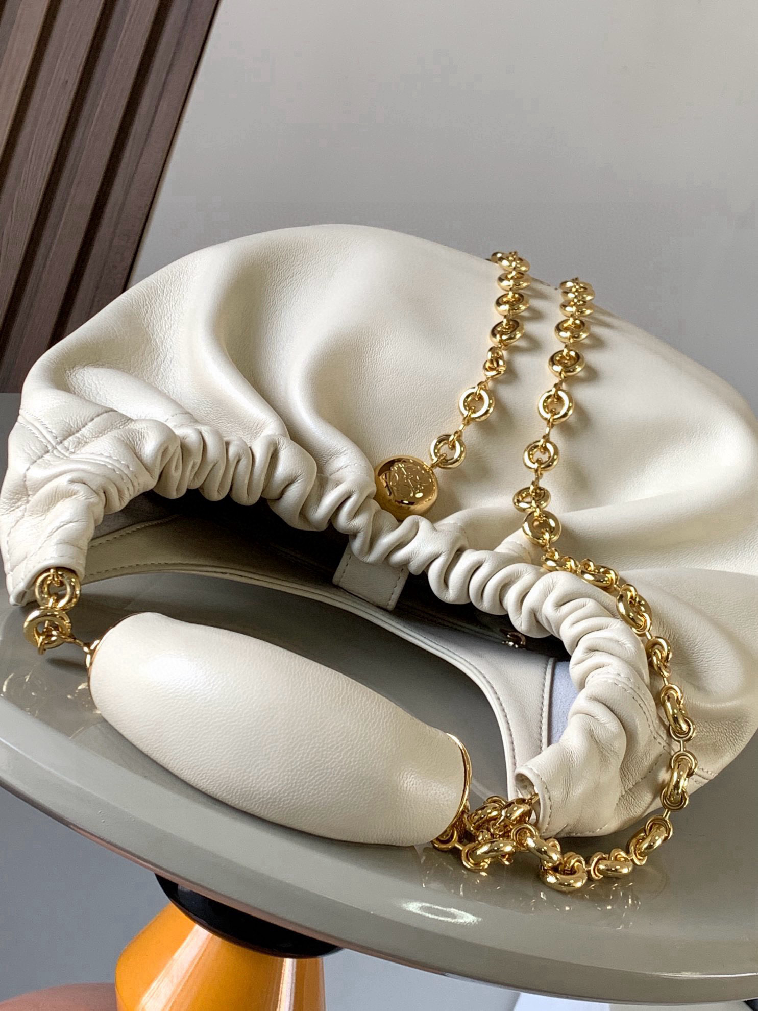 p980。🔥【明星同款】小号纳帕羊皮革Squeeze手袋💄是款精致而柔美的全新手袋💥全新发布的 Squeeze 手袋采用柔软丝滑的Mellow纳帕小羊皮制作而成❤️无衬里结构有效减轻包身自重🌺观感上也更为轻盈⭐️弯月形包口以优雅的褶边收口，营造出轻松又随性的态度👜这款包包还有一大亮点是符合人体工程学的 Squeeze 气囊手柄🌼搭配黄铜打造的精美甜甜圈链条😘可通过链环调节长短或添加延长链，实现手拎、肩背、斜挎等不同背法😻气囊手柄可自由滑动位置以提升舒适度🌻链条底部点缀一枚 Anagram Pebble 吊坠，为包包增添灵动细节⚡️
尺寸：29CM～24CM～10.5CM
款号：9042
颜色：柔白色