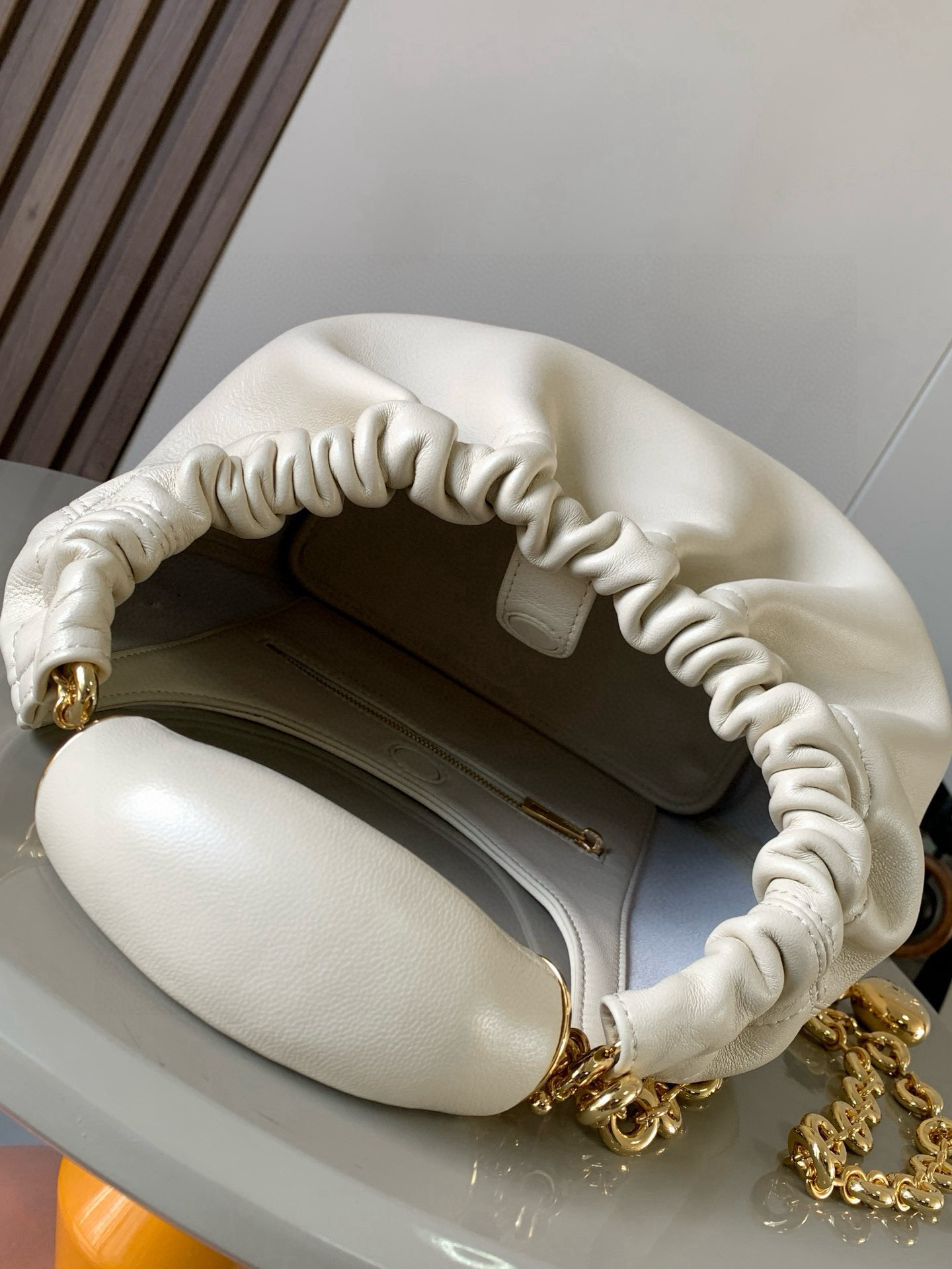 p980。🔥【明星同款】小号纳帕羊皮革Squeeze手袋💄是款精致而柔美的全新手袋💥全新发布的 Squeeze 手袋采用柔软丝滑的Mellow纳帕小羊皮制作而成❤️无衬里结构有效减轻包身自重🌺观感上也更为轻盈⭐️弯月形包口以优雅的褶边收口，营造出轻松又随性的态度👜这款包包还有一大亮点是符合人体工程学的 Squeeze 气囊手柄🌼搭配黄铜打造的精美甜甜圈链条😘可通过链环调节长短或添加延长链，实现手拎、肩背、斜挎等不同背法😻气囊手柄可自由滑动位置以提升舒适度🌻链条底部点缀一枚 Anagram Pebble 吊坠，为包包增添灵动细节⚡️
尺寸：29CM～24CM～10.5CM
款号：9042
颜色：柔白色