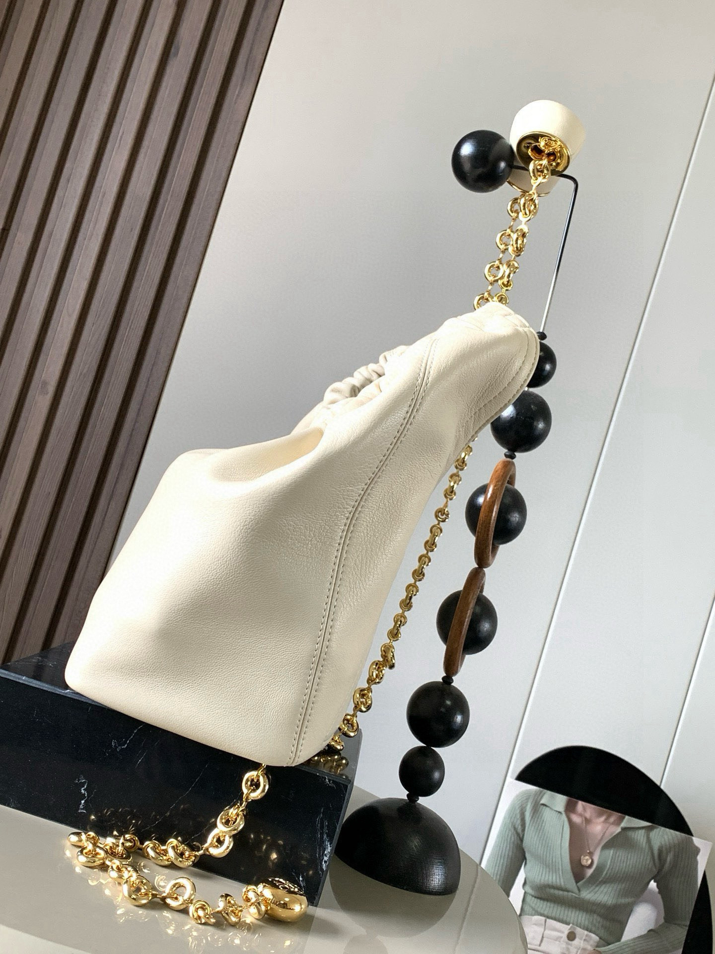 p980。🔥【明星同款】小号纳帕羊皮革Squeeze手袋💄是款精致而柔美的全新手袋💥全新发布的 Squeeze 手袋采用柔软丝滑的Mellow纳帕小羊皮制作而成❤️无衬里结构有效减轻包身自重🌺观感上也更为轻盈⭐️弯月形包口以优雅的褶边收口，营造出轻松又随性的态度👜这款包包还有一大亮点是符合人体工程学的 Squeeze 气囊手柄🌼搭配黄铜打造的精美甜甜圈链条😘可通过链环调节长短或添加延长链，实现手拎、肩背、斜挎等不同背法😻气囊手柄可自由滑动位置以提升舒适度🌻链条底部点缀一枚 Anagram Pebble 吊坠，为包包增添灵动细节⚡️
尺寸：29CM～24CM～10.5CM
款号：9042
颜色：柔白色