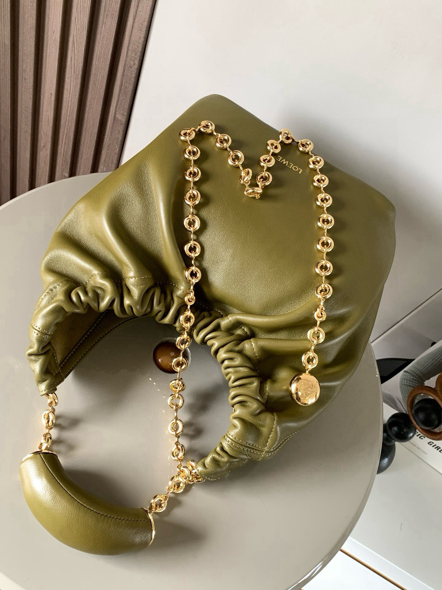 p980。🔥【明星同款】小号纳帕羊皮革Squeeze手袋💄是款精致而柔美的全新手袋💥全新发布的 Squeeze 手袋采用柔软丝滑的Mellow纳帕小羊皮制作而成❤️无衬里结构有效减轻包身自重🌺观感上也更为轻盈⭐️弯月形包口以优雅的褶边收口，营造出轻松又随性的态度👜这款包包还有一大亮点是符合人体工程学的 Squeeze 气囊手柄🌼搭配黄铜打造的精美甜甜圈链条😘可通过链环调节长短或添加延长链，实现手拎、肩背、斜挎等不同背法😻气囊手柄可自由滑动位置以提升舒适度🌻链条底部点缀一枚 Anagram Pebble 吊坠，为包包增添灵动细节⚡️
尺寸：29CM～24CM～10.5CM
款号：9042
颜色：橄榄绿