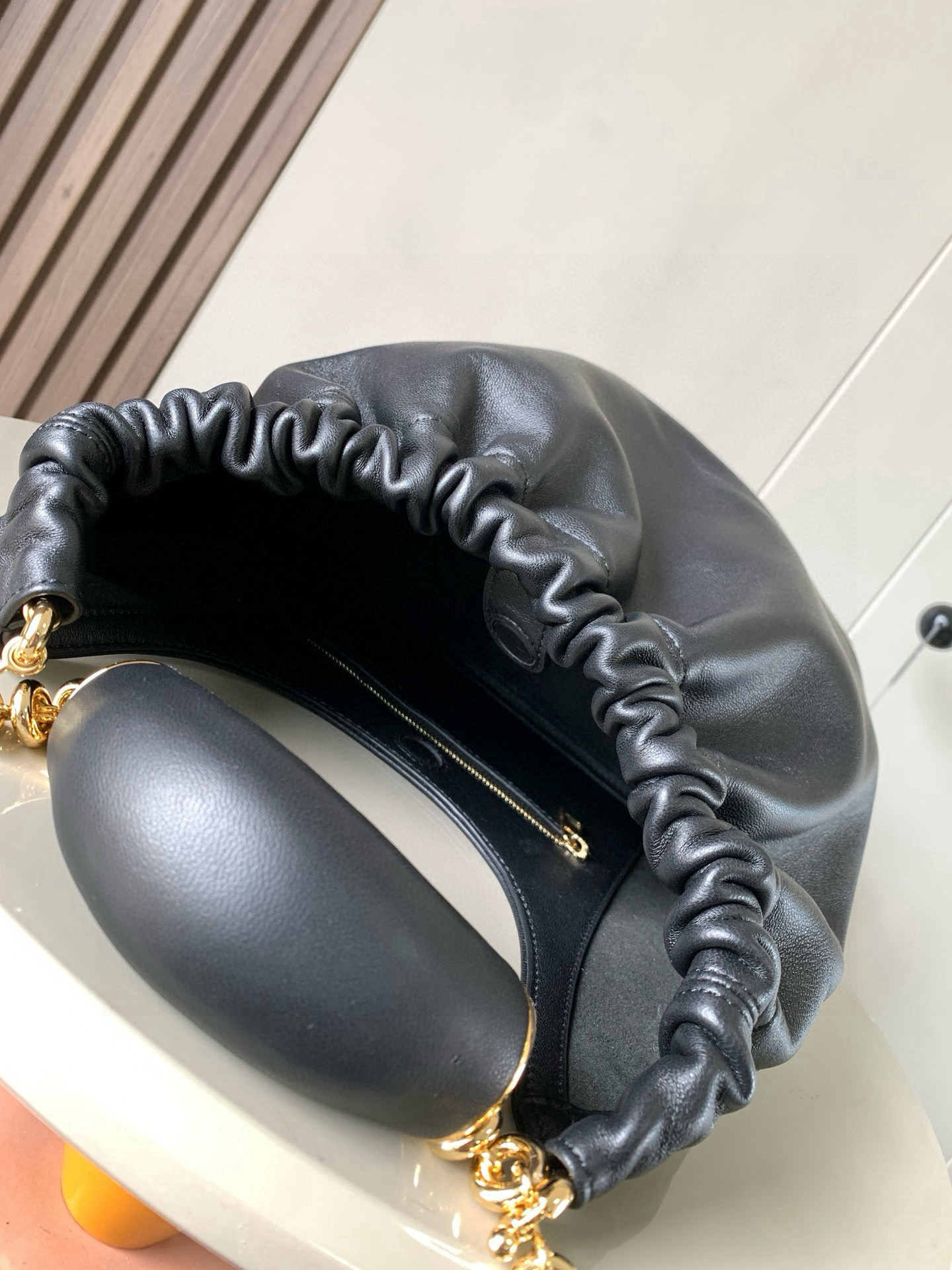 p980。🔥【明星同款】小号纳帕羊皮革Squeeze手袋💄是款精致而柔美的全新手袋💥全新发布的 Squeeze 手袋采用柔软丝滑的Mellow纳帕小羊皮制作而成❤️无衬里结构有效减轻包身自重🌺观感上也更为轻盈⭐️弯月形包口以优雅的褶边收口，营造出轻松又随性的态度👜这款包包还有一大亮点是符合人体工程学的 Squeeze 气囊手柄🌼搭配黄铜打造的精美甜甜圈链条😘可通过链环调节长短或添加延长链，实现手拎、肩背、斜挎等不同背法😻气囊手柄可自由滑动位置以提升舒适度🌻链条底部点缀一枚 Anagram Pebble 吊坠，为包包增添灵动细节⚡️
尺寸：29CM～24CM～10.5CM
款号：9042
颜色：黑色