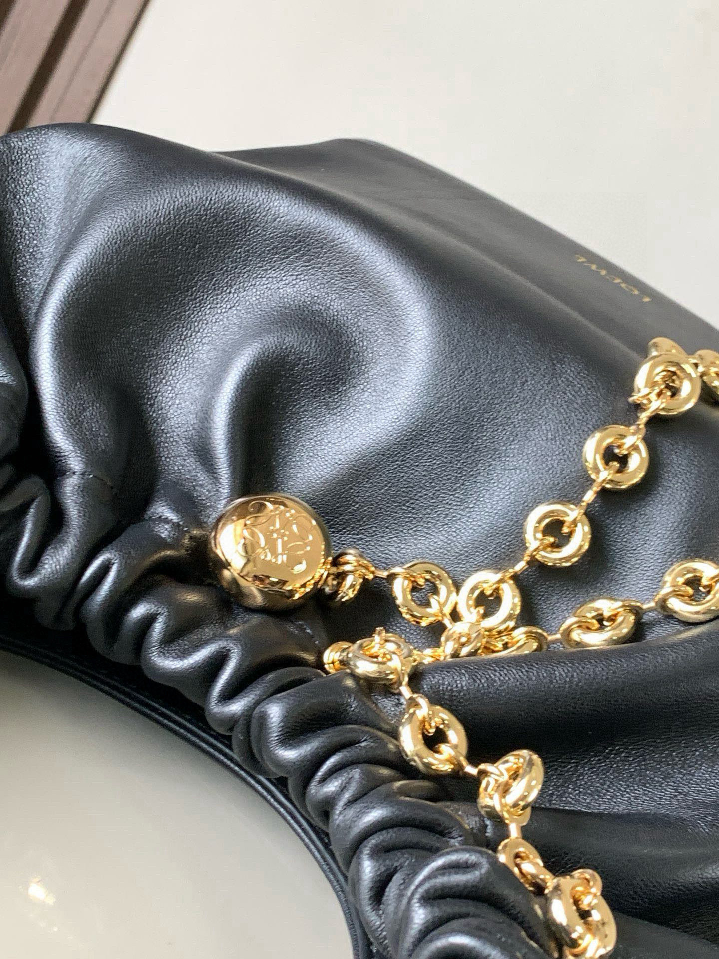 p980。🔥【明星同款】小号纳帕羊皮革Squeeze手袋💄是款精致而柔美的全新手袋💥全新发布的 Squeeze 手袋采用柔软丝滑的Mellow纳帕小羊皮制作而成❤️无衬里结构有效减轻包身自重🌺观感上也更为轻盈⭐️弯月形包口以优雅的褶边收口，营造出轻松又随性的态度👜这款包包还有一大亮点是符合人体工程学的 Squeeze 气囊手柄🌼搭配黄铜打造的精美甜甜圈链条😘可通过链环调节长短或添加延长链，实现手拎、肩背、斜挎等不同背法😻气囊手柄可自由滑动位置以提升舒适度🌻链条底部点缀一枚 Anagram Pebble 吊坠，为包包增添灵动细节⚡️
尺寸：29CM～24CM～10.5CM
款号：9042
颜色：黑色