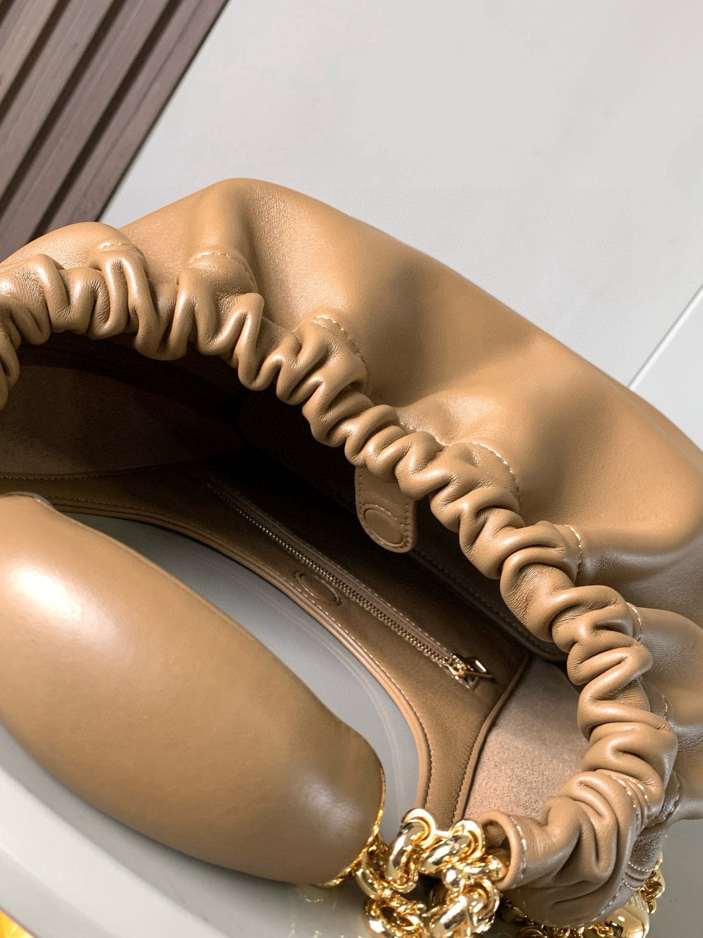 p980。🔥【明星同款】小号纳帕羊皮革Squeeze手袋💄是款精致而柔美的全新手袋💥全新发布的 Squeeze 手袋采用柔软丝滑的Mellow纳帕小羊皮制作而成❤️无衬里结构有效减轻包身自重🌺观感上也更为轻盈⭐️弯月形包口以优雅的褶边收口，营造出轻松又随性的态度👜这款包包还有一大亮点是符合人体工程学的 Squeeze 气囊手柄🌼搭配黄铜打造的精美甜甜圈链条😘可通过链环调节长短或添加延长链，实现手拎、肩背、斜挎等不同背法😻气囊手柄可自由滑动位置以提升舒适度🌻链条底部点缀一枚 Anagram Pebble 吊坠，为包包增添灵动细节⚡️
尺寸：29CM～24CM～10.5CM
款号：9042
颜色：橡木棕