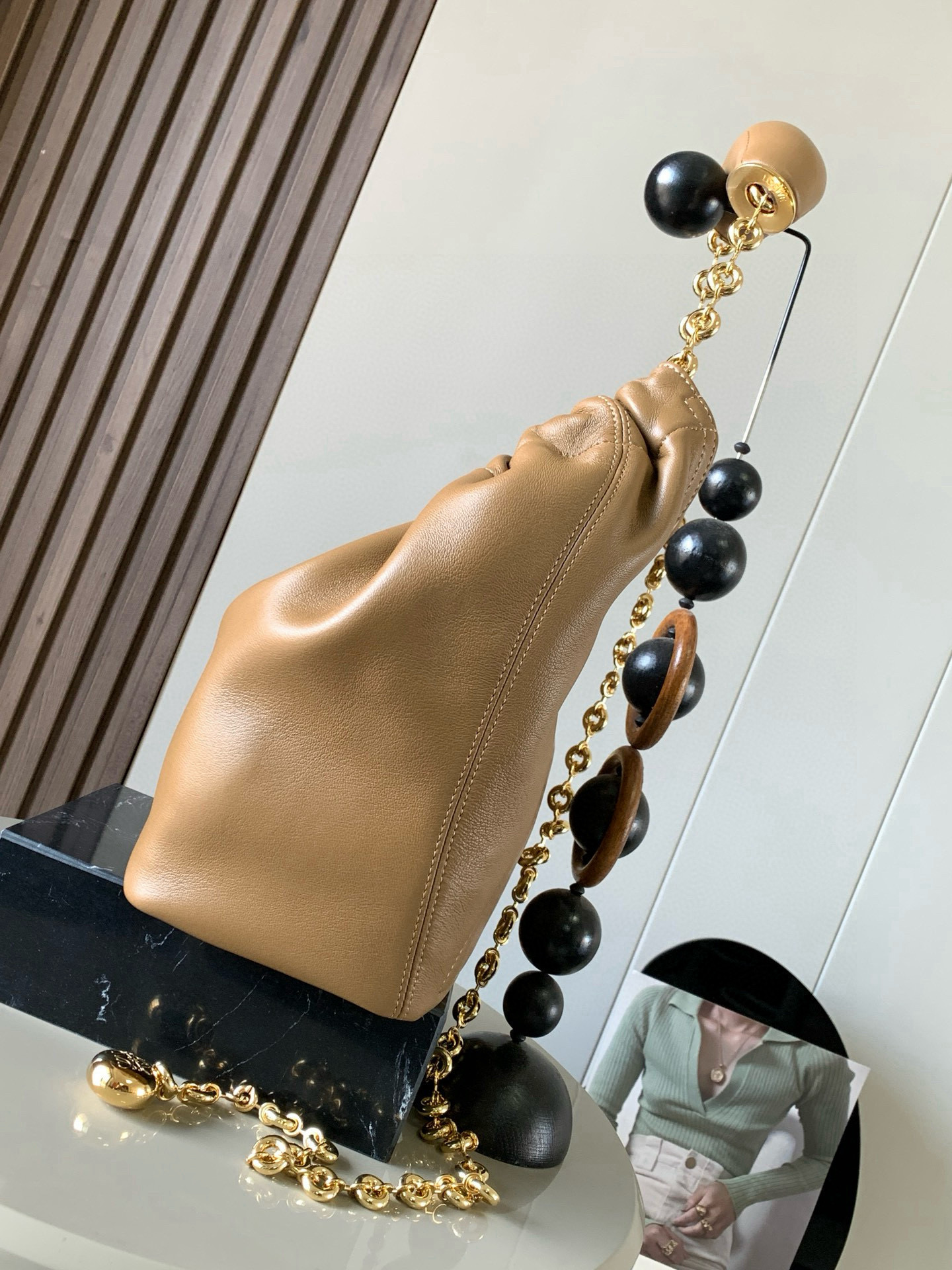 p980。🔥【明星同款】小号纳帕羊皮革Squeeze手袋💄是款精致而柔美的全新手袋💥全新发布的 Squeeze 手袋采用柔软丝滑的Mellow纳帕小羊皮制作而成❤️无衬里结构有效减轻包身自重🌺观感上也更为轻盈⭐️弯月形包口以优雅的褶边收口，营造出轻松又随性的态度👜这款包包还有一大亮点是符合人体工程学的 Squeeze 气囊手柄🌼搭配黄铜打造的精美甜甜圈链条😘可通过链环调节长短或添加延长链，实现手拎、肩背、斜挎等不同背法😻气囊手柄可自由滑动位置以提升舒适度🌻链条底部点缀一枚 Anagram Pebble 吊坠，为包包增添灵动细节⚡️
尺寸：29CM～24CM～10.5CM
款号：9042
颜色：橡木棕