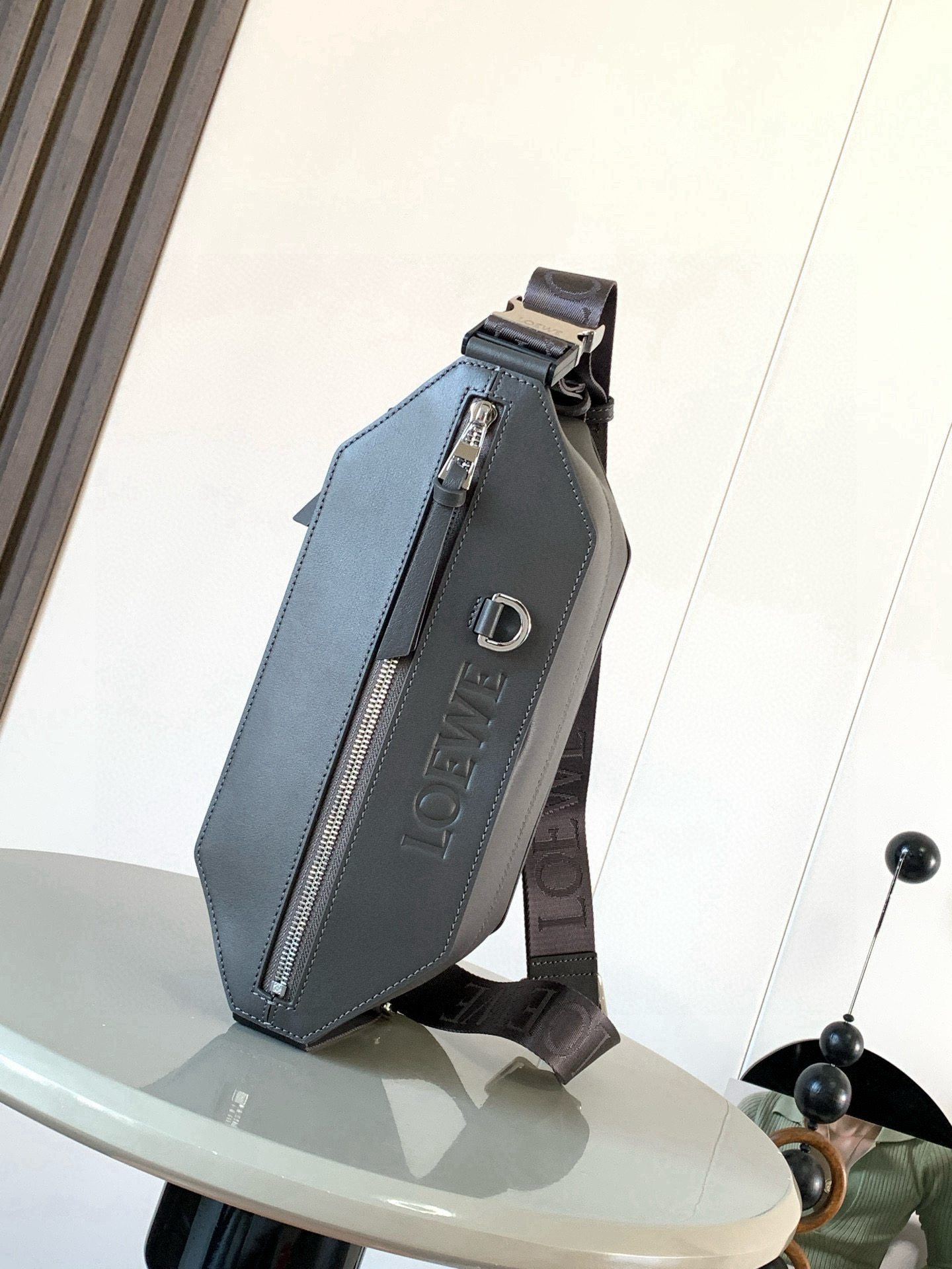 NO:659373,Classic cow leather variant Sling bag Compact Sling bag with adjustable LOEWE webbing and brand-signed metal buckle that opens to change the bag's capacity and allow for multiple carrying methods. External zippered flat pockets enhance functionality This version is crafted from classic cow leather. *Can be worn cross-body or as a belt bag  Size 32.5cm～9cm～12.3cm Style number 9074 Color dark coffee, Loewe, loewe, loewe, cowhide19860909经典牛皮革变形 Sling 手袋 紧凑型 Sling 手袋配有可调节 LOEWE 织带和品牌标志金属搭扣可打开以改变手袋容量并实现多种携带方式.外部拉链平口袋进步增强了功能性这个版本采用经典牛皮革制成.＊可斜挎或作为腰包携带＊拉链开合,牛皮革拉链头＊人字纹棉质帆布衬里＊配有 D 形环的压纹 LOEWE 尺寸32.5cm～9cm～12.3cm 款号9074 颜色深咖啡,罗意威,loewe,loewe,cowhide,Bag