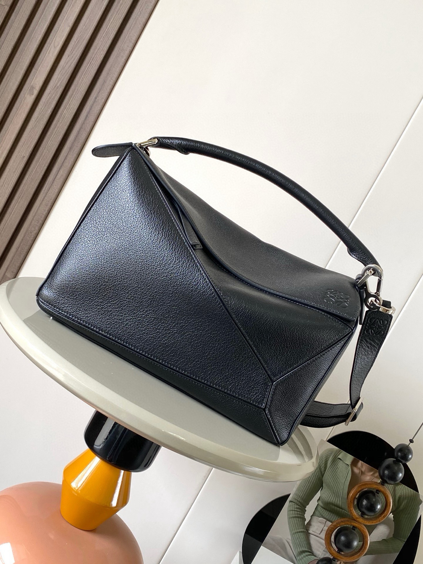 NO:659393,The new Puzzle size handbag Puzzle handbag is the creative director of Jonathan.  Jonathan Anderson created Puzzle for LOEWE's first handbag with its rectangular shape and precise cutting techniques  Unique geometric lines This version is made of glossy cow leather with overlapping edges * Can be worn on the shoulder, cross-body or by hand * Detachable and adjustable shoulder strap * External rear zip pocket and two internal slip pockets * Zipper closure cow leather zipper pull * Can be customized with shoulder straps and personalized charms * Suede lining * Anagram embossing Suitable for different occasions Unisex  Size 33cm～14.7cm～21.5cm Style number 9095 Color black, Loewe, loewe, loewe, cowhide19860909新款Puzzle尺寸手袋Puzzle 手袋是创意总监乔纳森．安德森（ Jonathan Anderson）为 LOEWE 推出的首款手提包长方体形状和精确的切割技术创造了 Puzzle 独特的几何线条此版本采用亮面牛皮革制成饰有重叠边缘＊可肩背、斜挎或手提＊可拆卸可调节肩带＊外部后方拉链袋和两个内部插袋＊拉链开合牛皮革拉链头＊可以使用肩带和个性化挂饰进行定制＊绒面革衬里＊ Anagram 压纹 满足不同场合需求男女通用 尺寸33cm～14.7cm～21.5cm 款号9095 颜色黑色,罗意威,loewe,loewe,cowhide,Bag