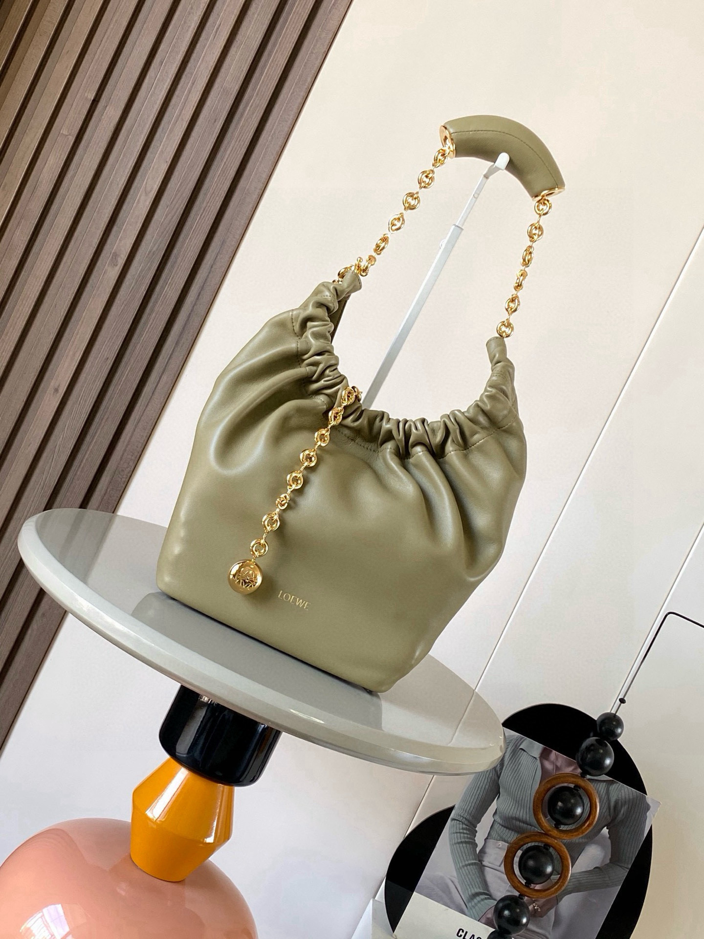 NO:719536,[Celebrity Style] Small Nappa Lamb Leather Squeeze Handbag is a refined and feminine new handbag. The newly released Squeeze Handbag is made of soft and silky Mellow Nappa lambskin. The unlined structure effectively reduces the weight of the bag and makes it lighter in appearance. The crescent-shaped bag mouth is closed with elegant ruffles, creating a relaxed and casual attitude. Another highlight of this bag is the ergonomic Squeeze  The airbag handle is matched with a delicate donut chain made of brass. The length can be adjusted through the chain link or an extension chain can be added to realize different carrying methods such as hand carry, shoulder carry, crossbody, etc. The airbag handle can slide freely to improve comfort. An Anagram Pebble pendant is embellished at the bottom of the chain to add smart details to the bag. Size 29CM～24CM～10.5CM Style No. 9042 Color Vetiver green, Loewe, loewe, sheepskin19860909【明星同款】小号纳帕羊皮革Squeeze手袋是款精致而柔美的全新手袋全新发布的 Squeeze 手袋采用柔软丝滑的Mellow纳帕小羊皮制作而成无衬里结构有效减轻包身自重观感上也更为轻盈弯月形包口以优雅的褶边收口,营造出轻松又随性的态度这款包包还有一大亮点是符合人体工程学的 Squeeze 气囊手柄搭配黄铜打造的精美甜甜圈链条可通过链环调节长短或添加延长链,实现手拎、肩背、斜挎等不同背法气囊手柄可自由滑动位置以提升舒适度链条底部点缀一枚 Anagram Pebble 吊坠为包包增添灵动细节 尺寸29CM～24CM～10.5CM 款号9042 颜色香根草绿,罗意威,loewe,sheepskin,Bag