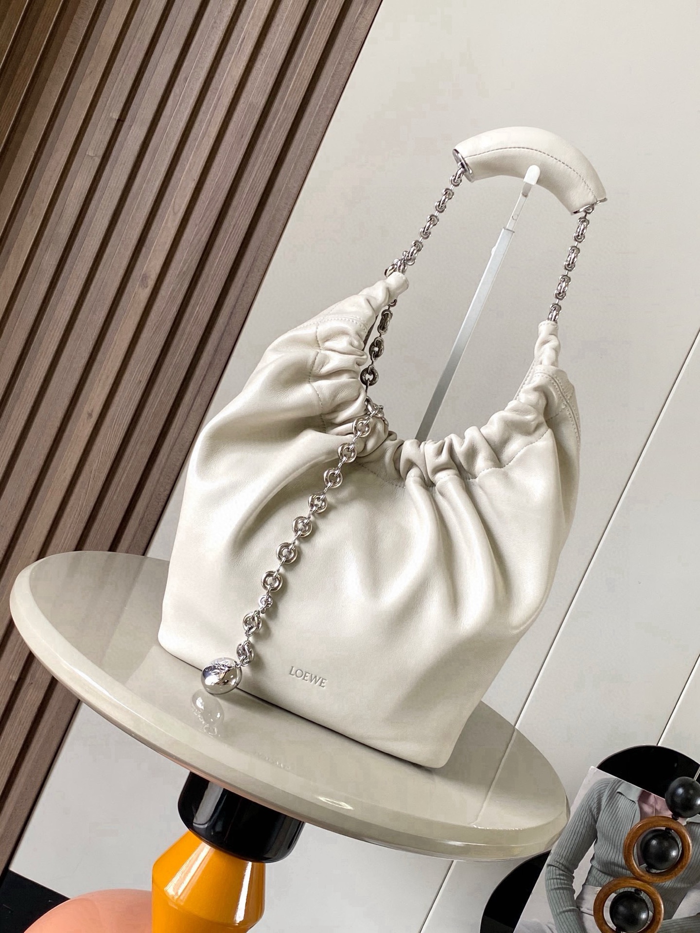 NO:719539,[Celebrity Style] Small Nappa Lamb Leather Squeeze Handbag is a refined and feminine new handbag. The newly released Squeeze Handbag is made of soft and silky Mellow Nappa lambskin. The unlined structure effectively reduces the weight of the bag and makes it lighter in appearance. The crescent-shaped bag mouth is closed with elegant ruffles, creating a relaxed and casual attitude. Another highlight of this bag is the ergonomic Squeeze  The airbag handle is matched with a delicate donut chain made of brass. The length can be adjusted through the chain link or an extension chain can be added to realize different carrying methods such as hand carry, shoulder carry, crossbody, etc. The airbag handle can slide freely to improve comfort. An Anagram Pebble pendant is embellished at the bottom of the chain to add smart details to the bag. Size 29CM～24CM～10.5CM Style No. 9042 Color sea salt white, Loewe, loewe, sheepskin19860909【明星同款】小号纳帕羊皮革Squeeze手袋是款精致而柔美的全新手袋全新发布的 Squeeze 手袋采用柔软丝滑的Mellow纳帕小羊皮制作而成无衬里结构有效减轻包身自重观感上也更为轻盈弯月形包口以优雅的褶边收口,营造出轻松又随性的态度这款包包还有一大亮点是符合人体工程学的 Squeeze 气囊手柄搭配黄铜打造的精美甜甜圈链条可通过链环调节长短或添加延长链,实现手拎、肩背、斜挎等不同背法气囊手柄可自由滑动位置以提升舒适度链条底部点缀一枚 Anagram Pebble 吊坠为包包增添灵动细节 尺寸29CM～24CM～10.5CM 款号9042 颜色海盐白,罗意威,loewe,sheepskin,Bag