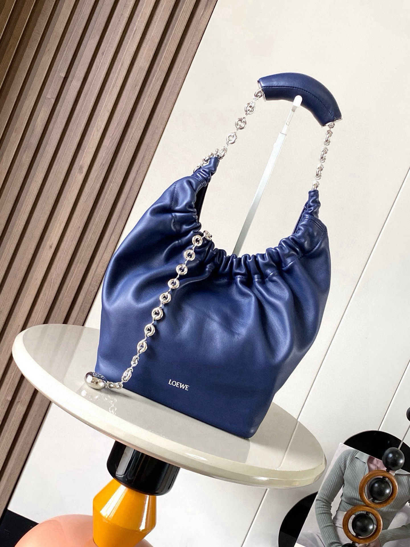 NO:719542,[Celebrity Style] Small Nappa Lamb Leather Squeeze Handbag is a refined and feminine new handbag. The newly released Squeeze Handbag is made of soft and silky Mellow Nappa lambskin. The unlined structure effectively reduces the weight of the bag and makes it lighter in appearance. The crescent-shaped bag mouth is closed with elegant ruffles, creating a relaxed and casual attitude. Another highlight of this bag is the ergonomic Squeeze  The air bag handle is matched with a delicate donut chain made of brass. The length can be adjusted through the chain link or an extension chain can be added to realize different carrying methods such as hand carry, shoulder carry, cross body, etc. The air bag handle can slide freely to improve comfort. An Anagram Pebble pendant is embellished at the bottom of the chain to add smart details to the bag. Size 29CM～24CM～10.5CM Style No. 9042 Color Navy blue, Loewe, loewe, sheepskin19860909【明星同款】小号纳帕羊皮革Squeeze手袋是款精致而柔美的全新手袋全新发布的 Squeeze 手袋采用柔软丝滑的Mellow纳帕小羊皮制作而成无衬里结构有效减轻包身自重观感上也更为轻盈弯月形包口以优雅的褶边收口,营造出轻松又随性的态度这款包包还有一大亮点是符合人体工程学的 Squeeze 气囊手柄搭配黄铜打造的精美甜甜圈链条可通过链环调节长短或添加延长链,实现手拎、肩背、斜挎等不同背法气囊手柄可自由滑动位置以提升舒适度链条底部点缀一枚 Anagram Pebble 吊坠为包包增添灵动细节 尺寸29CM～24CM～10.5CM 款号9042 颜色海军蓝,罗意威,loewe,sheepskin,Bag