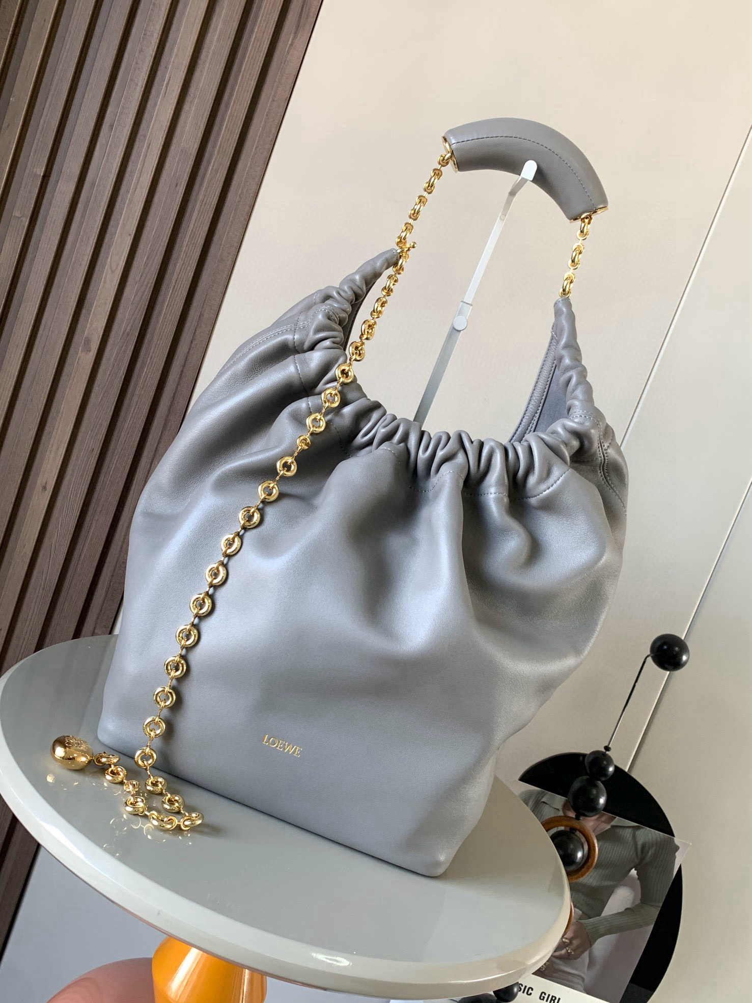 NO:719552,[Celebrity Style] Medium Nappa Lamb Leather Squeeze Handbag is a refined and feminine new handbag. The newly released Squeeze Handbag is made of soft and silky Mellow Nappa lambskin. The unlined structure effectively reduces the weight of the bag and makes it lighter in appearance. The crescent-shaped bag mouth is closed with elegant ruffles, creating a relaxed and casual attitude. Another highlight of this bag is the ergonomic Squeeze  The airbag handle is paired with a delicate donut chain made of brass. The length can be adjusted through the chain link or an extension chain can be added to realize different carrying methods such as hand carry, shoulder carry, and crossbody. The airbag handle can slide freely to improve comfort. An Anagram Pebble pendant is embellished at the bottom of the chain to add smart details to the bag. Size 34CM～33CM～13.5CM Style No. 9041 Color Pearl Gray, Loewe, Loewe, Sheepskin19860909【明星同款】中号纳帕羊皮革Squeeze手袋是款精致而柔美的全新手袋全新发布的 Squeeze 手袋采用柔软丝滑的Mellow纳帕小羊皮制作而成无衬里结构有效减轻包身自重观感上也更为轻盈弯月形包口以优雅的褶边收口,营造出轻松又随性的态度这款包包还有一大亮点是符合人体工程学的 Squeeze 气囊手柄搭配黄铜打造的精美甜甜圈链条可通过链环调节长短或添加延长链,实现手拎、肩背、斜挎等不同背法气囊手柄可自由滑动位置以提升舒适度链条底部点缀一枚 Anagram Pebble 吊坠,为包包增添灵动细节 尺寸34CM～33CM～13.5CM 款号9041 颜色珍珠灰,罗意威,loewe,sheepskin,Bag