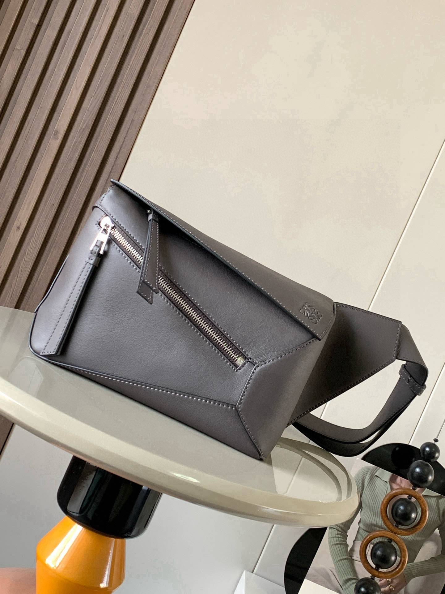 NO:719598,The new small classic cow leather Puzzle waist bag has a rectangular shape and precise cutting technology to create Puzzle's unique geometric lines. This small waist bag is made of classic cow leather. The leather is soft and lightweight, and the shape is low-key and recognizable. It can be worn with the back, whether it is business or leisure. I found a puzzle waist bag, which is relatively classic and puzzle is relatively niche. This waist bag removes the handle of the classic puzzle and puts the classic puzzle  The rear zipper bag has been moved to the front and the belt has become a non-detachable latch buckle. The wide belt retains the classic puzzle casual and artistic basic bag shape, and the fork adds a cool mechanical feel. It is also classic and versatile. It not only has a considerable capacity but also has a better upper body proportion. It can be carried on the shoulder or cross-body, with an adjustable shoulder strap and a metal buckle opening and closing. Size 24CM～16CM～10.5CM. Style No. 9114  Color gray coffee, Loewe, loewe, cowhide19860909新款小号经典牛皮革 Puzzle 腰包长方体形状和精确的切割技术创造了Puzzle 独特的几何线条这款小号腰包采用经典牛皮革制成皮质柔软轻便,造型低调有辨识度不管是商务还是休闲都可以搭配后来叉发现一款 puzzle腰包,相对经典,puzzle 来说比较小众此款腰包去掉了经典puzzle的手柄把经典puzzle 后面的后置拉链袋移到了前面腰带也变成不可拆卸插销扣宽腰带保留经典puzzle随性文艺的基本包型外,叉增加了一份酷酷的机械感同样经典百搭. 不仅容量可观而且上身比例更好.肩背或斜挎 ,可调节肩带,配有金属搭扣开合 尺寸24CM～16CM～10.5CM 款号9114 颜色灰咖色,罗意威,loewe,cowhide,Bag