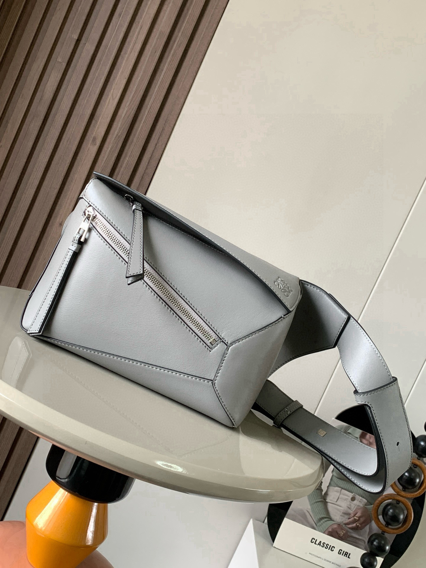 NO:719607,The new small classic cow leather Puzzle waist bag has a rectangular shape and precise cutting technology to create Puzzle's unique geometric lines. This small waist bag is made of classic cow leather. The leather is soft and lightweight, and the shape is low-key and recognizable. It can be worn with the back, whether it is business or leisure. I found a puzzle waist bag, which is relatively classic and puzzle is relatively niche. This waist bag removes the handle of the classic puzzle and puts the classic puzzle  The rear zipper bag has been moved to the front belt and has become a non-detachable latch buckle wide belt. In addition to retaining the classic puzzle casual and literary basic bag shape, the fork adds a cool mechanical feel and is also classic and versatile. Not only does it have a considerable capacity, but it also has a better upper body proportion. It can be carried on the shoulder or crossbody, adjustable shoulder strap, equipped with metal buckle closure. Size 24CM～16CM～10.5CM. Style No. 9114. Color: asphalt gray, Loewe, loewe, cowhide.19860909新款小号经典牛皮革 Puzzle 腰包长方体形状和精确的切割技术创造了Puzzle 独特的几何线条这款小号腰包采用经典牛皮革制成皮质柔软轻便,造型低调有辨识度不管是商务还是休闲都可以搭配后来叉发现一款 puzzle腰包,相对经典,puzzle 来说比较小众此款腰包去掉了经典puzzle的手柄把经典puzzle 后面的后置拉链袋移到了前面腰带也变成不可拆卸插销扣宽腰带保留经典puzzle随性文艺的基本包型外,叉增加了一份酷酷的机械感同样经典百搭. 不仅容量可观而且上身比例更好.肩背或斜挎 ,可调节肩带,配有金属搭扣开合 尺寸24CM～16CM～10.5CM 款号9114 颜色沥青灰,罗意威,loewe,cowhide,Bag