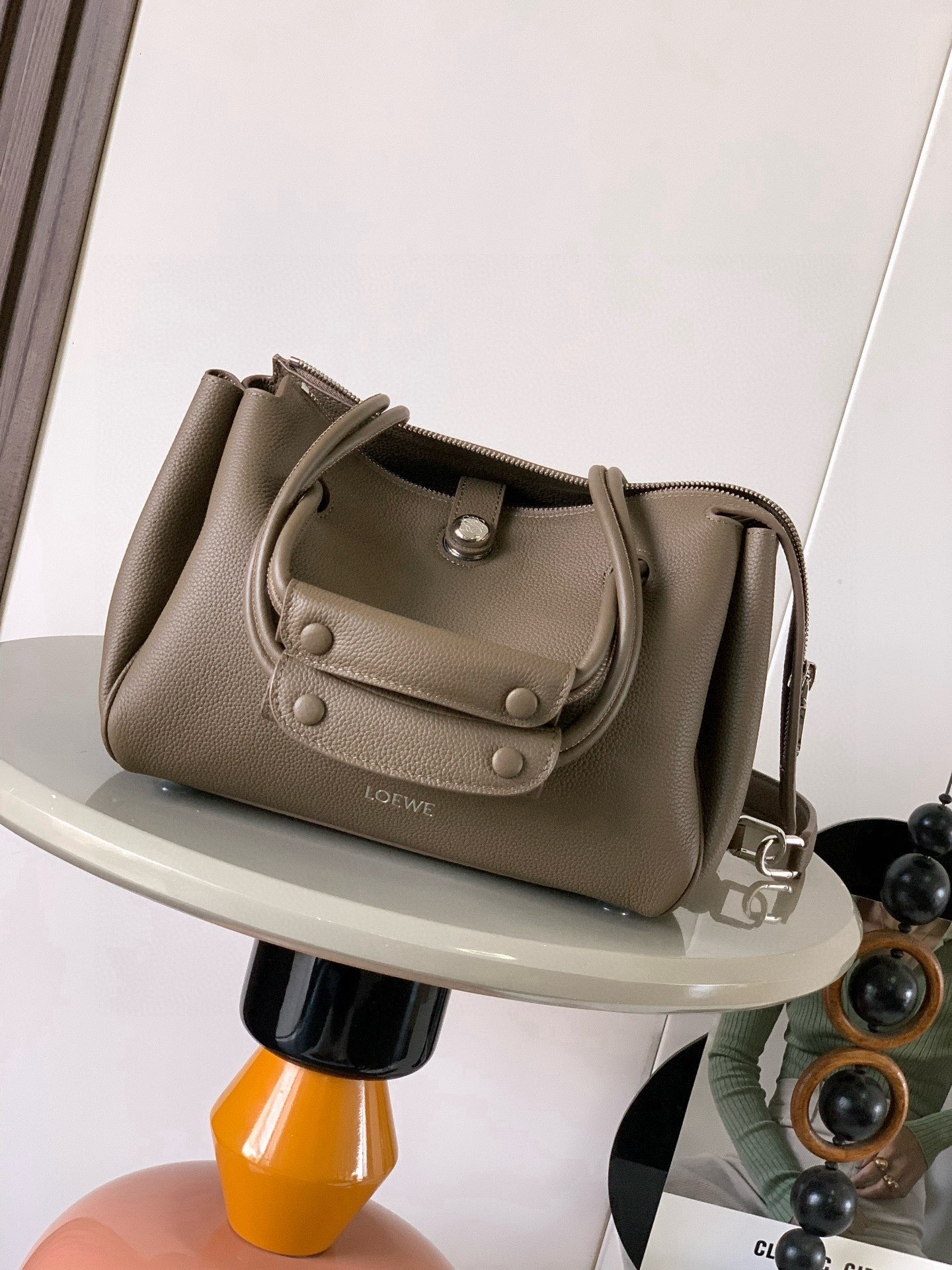 NO:719625,Small Madrid bag in soft calfskin Madrid has a soft structured trapezoidal shape with gusseted design, adjustable handles and Pebble magnetic closure This small version is made of soft calfskin *Can be worn on the shoulder, crossbody or by hand *Adjustable shoulder strap with leather extension *AnagramPebble magnetic zipper closure *One zipped interior pocket *Anagram Pebble metal feet *Nappa sheepskin lining  Size 23.5CM～19CM～10CM Style No. 9146 Color Taupe Li, Loewe, loewe, cowhide, sheepskin19860909小号柔软牛皮革 Madrid手袋Madrid 具有柔软的结构感梯形造型采用角撑设计,搭配可调节提手和 Pebble 磁扣此小号版本采用柔软牛皮革制成*可肩背、斜挎或手提*可调节肩带,搭配皮革延长带 *AnagramPebble 磁扣开合拉链开合*一个拉链内袋 *Anagram Pebble金属脚钉*纳帕羊皮革衬里 尺寸23.5CM～19CM～10CM 款号9146 颜色灰褐色荔,罗意威,loewe,cowhide,sheepskin,Bag