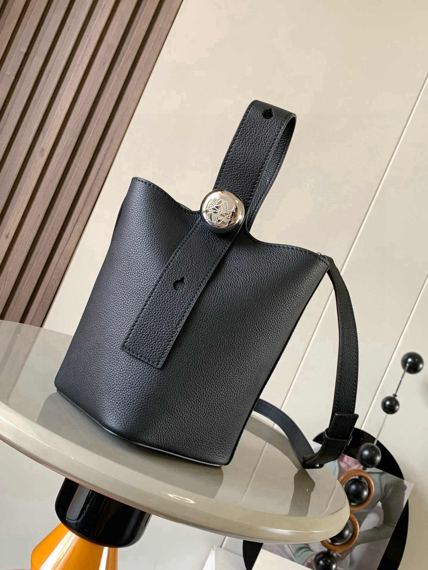 NO:719766,Mini soft grained calfskin Pebble Bucket Pebble cleverly combines pure simple lines with eye-catching design style to create a unique and innovative handbag design. Iconic Anagram  Engraved hardware is both decorative and practical, with an adjustable shoulder strap for multiple carry styles, with a unique twist complemented by subtle details. This mini version is crafted from soft grained calfskin. Can be worn cross-body, over the shoulder or by hand * Adjustable and removable shoulder strap * Magnetic closure * Internal pocket * Synthetic leather lining * Anagram Engraved Pebbles Style No. 9047 Color Black Lychee  Size 20CM～16CM～16CM, Loewe, loewe, cowhide19860909迷你柔软粒面牛皮革 Pebble Bucket 水桶手袋Pebble将纯粹的简约线条与瞩目设计风格巧妙融合造就别具一格的创新的手袋设计.标志性的 Anagram 雕刻五金件兼具装饰和实用功能,可调节肩带长度并适合多种携带方式,独特的扭曲结构与微妙的细节相得益彰.此迷你版本采用柔软粒面牛皮革制成.可斜挎、肩背或手提＊可调节可拆卸肩带＊磁扣开合＊内袋＊合成革衬里* Anagram 雕刻卵石 款号9047 颜色黑色荔 尺寸20CM～16CM～16CM,罗意威,loewe,cowhide,Bag