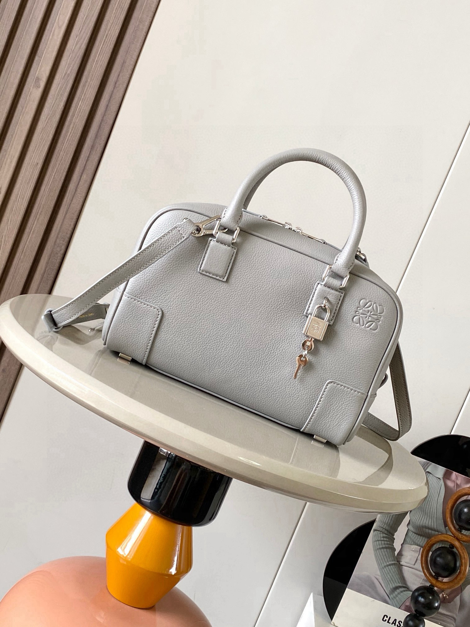 NO:770488,Amazona 23 Bag in Nappa Cow Leather The Amazona is LOEWE's iconic bag, originally launched in the 1970s as a top-handle soft-structure bag. This Nappa cow leather version is updated with refined proportions and details, including an Anagram  Engraved padlock * Cross-body, shoulder or top handle carry * Detachable and adjustable shoulder strap * Dual zipper closure * Cow leather zipper pull * Internal zip compartment and snap-fastened slip pocket * Mini pocket for padlock keys * Protective metal feet at base * Can be customized with shoulder strap and personalized charms * Gold suede lining * Anagram embossed  Size 23cm～10cm～15cm Style No. 9078 Color Gray Li, Loewe, loewe, loewe, cowhide19860909纳帕牛皮革 Amazona 23 手袋Amazona 是 LOEWE 的标志性手袋,最初于1970年代作为顶部提手软结构手袋推出这款纳帕牛皮革版本更新了精致的比例和细节,包括一个 Anagram 雕刻挂锁＊斜挎、肩背或顶部提手携带＊可拆卸可调节肩带＊双拉链开合＊牛皮革拉链头＊内部拉链隔层和按扣固定的插袋＊用于存放挂锁钥匙的迷你口袋＊底部保护性金属脚＊可以使用肩带和个性化挂饰进行定制＊金色绒面革衬里＊ Anagram 压纹 尺寸23cm～10cm～15cm 款号9078 颜色灰色荔,罗意威,loewe,loewe,cowhide,Bag