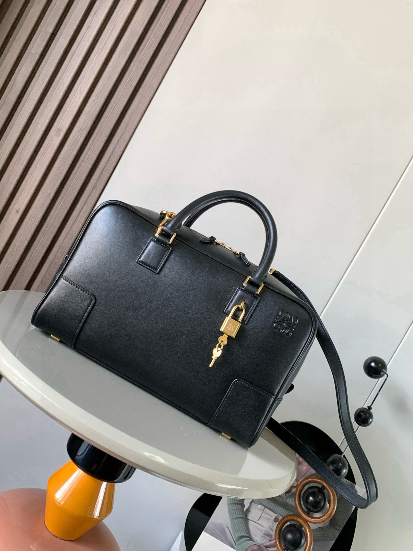NO:770495,Amazona 28 Handbag in Nappa Cow Leather The Amazona is LOEWE's iconic bag, originally launched in the 1970s as a top-handle soft-structure handbag. This Nappa cow leather version has been updated with refined proportions and details, including an Anagram  Engraved padlock * Cross-body, shoulder or top handle carry * Detachable and adjustable shoulder strap * Dual zipper closure * Cow leather zipper pull * Internal zip compartment and snap-fastened slip pocket * Mini pocket for padlock keys * Protective metal feet at base * Can be customized with shoulder strap and personalized charms * Gold suede lining * Anagram embossed  Size 28cm～11cm～18cm Style number 9080 Color black, Loewe, loewe, loewe, cowhide19860909纳帕牛皮革 Amazona 28手袋Amazona 是 LOEWE 的标志性手袋,最初于1970年代作为顶部提手软结构手袋推出这款纳帕牛皮革版本更新了精致的比例和细节,包括一个 Anagram 雕刻挂锁＊斜挎、肩背或顶部提手携带＊可拆卸可调节肩带＊双拉链开合＊牛皮革拉链头＊内部拉链隔层和按扣固定的插袋＊用于存放挂锁钥匙的迷你口袋＊底部保护性金属脚＊可以使用肩带和个性化挂饰进行定制＊金色绒面革衬里＊ Anagram 压纹 尺寸28cm～11cm～18cm 款号9080 颜色黑色,罗意威,loewe,loewe,cowhide,Bag