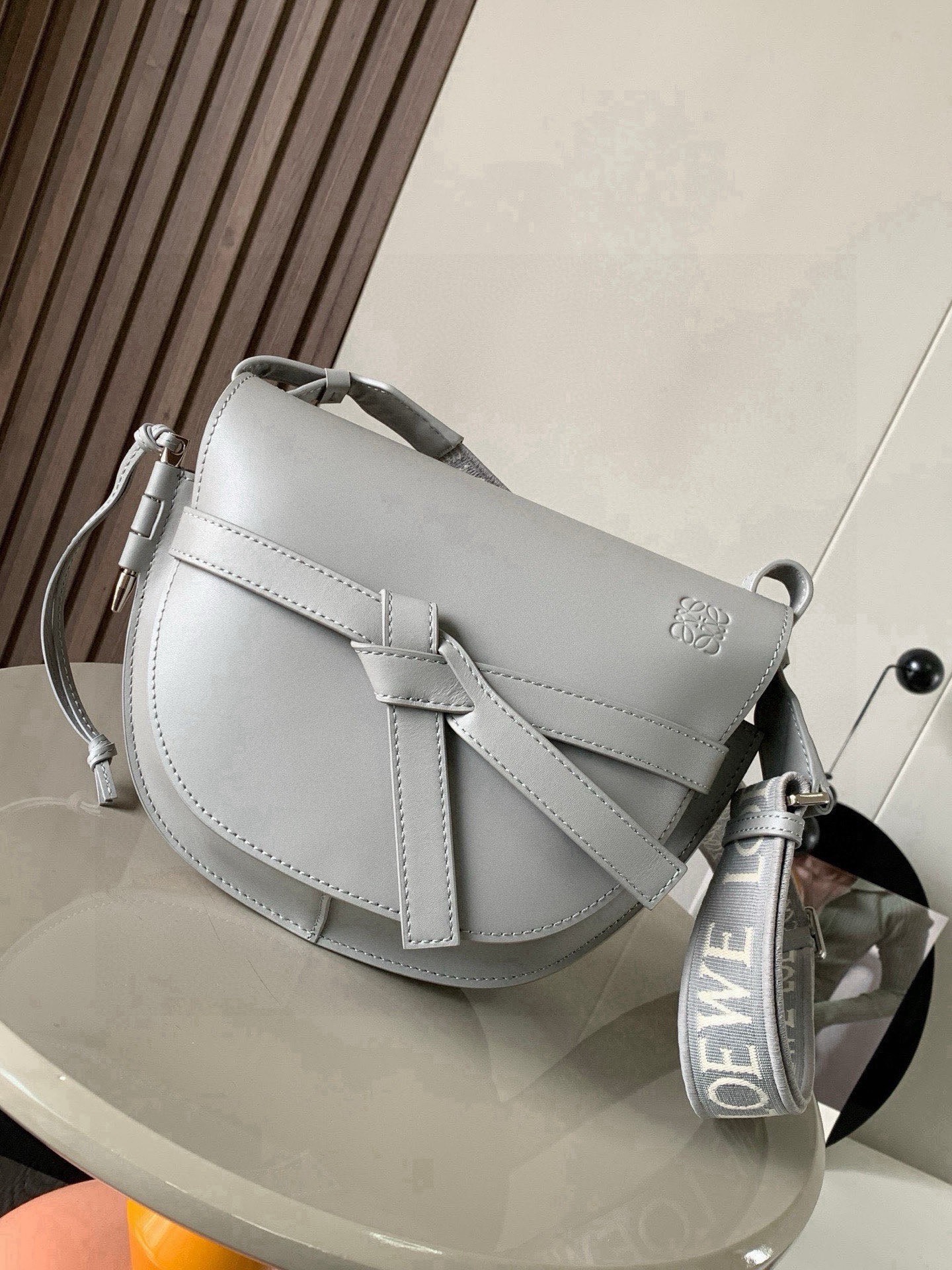 NO:853705,Popular small size 25CM new letter wide shoulder strap saddle bag Gate Duel handbag wide shoulder strap is simply the pen of the soul, giving gate a new life. The bag body is made of soft cow leather, removable and adjustable cowhide embroidered shoulder strap for single shoulder crossbody, waist bag and chest bag. The back and upper body are very elegant. The capacity is also very online. The bow is not only a decoration, but also the only socket on the bag cover. There is only one brand logo in the whole bag.  The bullet-type brass hosel has no other hardware accessories. It is completely made of high-end Western European traditional leather craftsmanship and design style. So it is lightweight and the shoulder straps can be adjusted in length. Girls of any height can control it. This is very nice. Size 25CM~19CM~11.5CM. Style No. 9004. Color: pearlescent gray, Loewe, loewe, cowhide.19860909爆款小号25CM新款字母宽肩带马鞍包Gate Duel手袋寛肩带简直是灵魂之笔赋予了gate全新的生命包身采用柔软牛皮革精制而成可拆卸调节牛皮提绣花肩带单肩斜挎、腰包 胸包都非常~背上身很显气质 容量也非常在线 蝴蝶结不仅是装饰,也是包盖的唯一插口全包只有一个带品牌精致logo 的子弹头式黄铜插鞘没有其他五金配件,完全是高大上的西欧传统皮革工艺性和设计风格So自重轻便,肩带调节长度,任何身高妹纸都可驾驭,这点很nice了 尺寸25CM~19CM~11.5CM 款号9004 颜色珠光灰,罗意威,loewe,cowhide,Bag