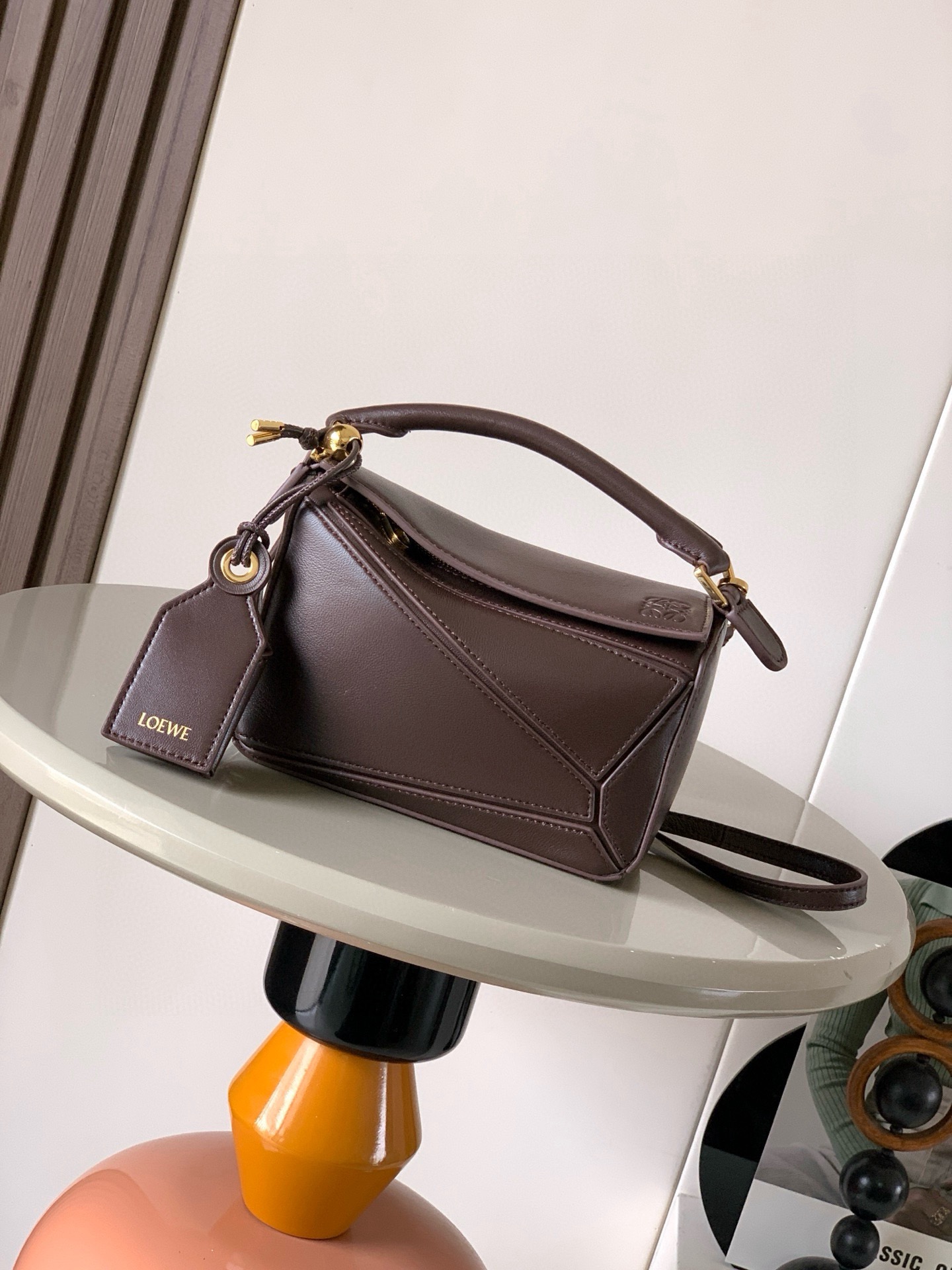 NO:854188,New version of the Geometric Bag Mini Nappa Lamb Leather Featherlight Puzzle Bag,  The original imported Napa calfskin outlines a cuboid shape with unique geometric lines. The soft and lightweight Napa leather injects a casual and lazy style into the handbag. *Can be carried on the shoulder, crossbody or handheld*Detachable and adjustable shoulder strap, decorated with rotating buckle*Zipper  Closure, articulated zipper pull * One external zipped back pocket, one internal slip pocket * Removable, with secret pocket and balloon dice * Rectangular metal feet * This smaller version is made from soft Nappa calf leather * Small Puzzle  Can hold, for example, a large wallet, all sizes of mobile phones and sunglasses, carried diagonally, on the shoulder, in hand or by top handle *Detachable Color Brownie Dark Brown Style No. 9098 Size 18CM～12.5CM～7.5CM, Loewe,thom browne,loewe,wallets,cowhide,sheepskin19860909新版本几何包迷你纳帕羊皮革 Featherlight Puzzle 手袋, 原厂进口纳帕小牛皮以别具一格的几何线条勾勒长方体造型.柔软轻盈的纳帕皮革为手袋注入随性慵懒的风格.*可肩背、斜挎或手提*可拆卸可调节肩带,饰有旋转卡扣*拉链开合,铰接式拉链头*一个外部拉链后袋,一个内部插袋*可拆卸,饰有隐秘口袋和气球骰子*长方形金属脚钉*这个小尺寸版本采用柔软纳帕小牛皮革制成＊小号Puzzle 可以容纳例如一只大号钱包所有尺寸的手机和太阳镜斜、肩背、手拿或顶部提手携带＊可拆卸 颜色布朗尼深棕 款号9098 尺寸18CM～12.5CM～7.5CM,罗意威,thom browne,loewe,wallets,cowhide,sheepskin,Bag