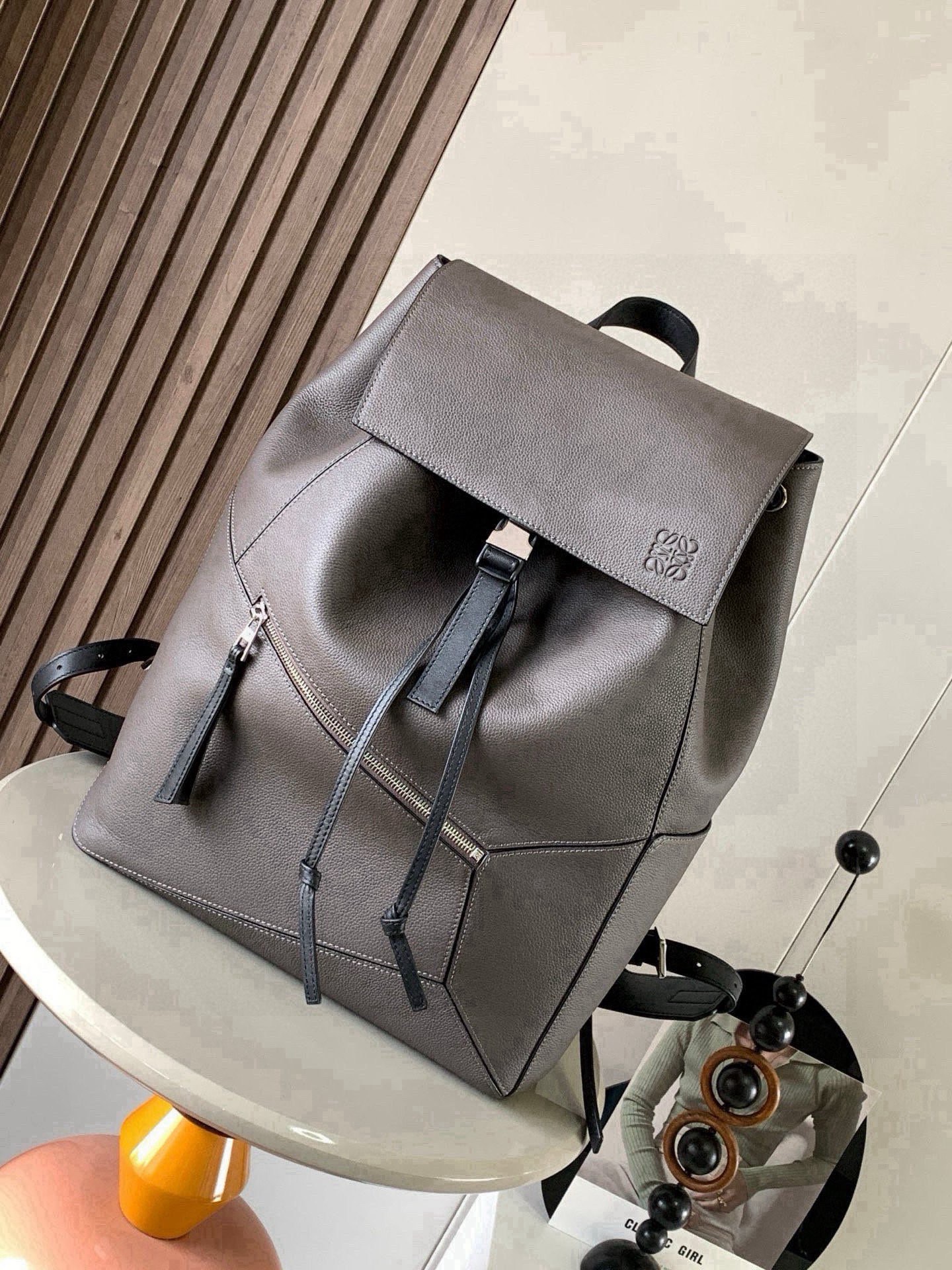 NO:854286,Puzzle Backpack Backpack Soft Grained Calf Leather Military Backpack Backpack is a spacious and versatile backpack style. The backpack is made of soft grained calfskin and classic calfskin. It is very comfortable to the touch. It is not only durable but also has a shoulder-stretching design. This backpack adopts Loewe's classic geometric design without a large logo.  You can directly recognize the low-key and connotative content by displaying it. Its cubic shape is unique and innovative, and the drawstring bag mouth is equipped with a buckle switch. It is safe and practical. The bag is basically versatile. Not only that, it also has a large capacity suitable for commuting and travel. Fashion and practicality coexist!  Size 33～44.5～16CM Style number 9031 Color gray, Loewe, loewe, backpacks, cowhide19860909puzzle Backpack双肩包柔软粒面牛皮革军用背包双肩包是一种宽敞且用途广泛的背包款双肩包选择的是用柔软粒面小牛皮与经典小牛皮精制而成触感非常的舒适,不仅抗造而且还不勒肩膀设计这款双肩包采用了罗意威家的经典几何设计不用大幅度的 logo 展示就可以直接辨认低调有内涵.其立方体的造型独特而创新,抽绳包口搭配搭扣开关,安全又实用包包基本百搭,不仅如此它还有超大容量适用于通勤和差旅时尚与实用并存！ 尺寸33～44.5～16CM 款号9031 颜色灰色,罗意威,loewe,backpacks,cowhide,Bag