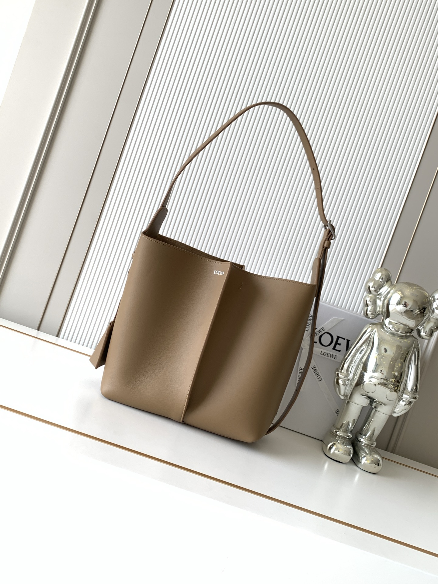 NO:854462,Medium Smooth Calf Leather Bilbao Bucket Bag Billbao trapezoidal bucket bag has a simple geometric design. Crafted from leather panels with pleats in the center, the shape is soft and close-fitting. Ideal for everyday carry. This medium version is made of smooth cow leather. * Can be worn on the shoulder or cross-body * Adjustable shoulder strap * Detachable Double L  Embossed leather bell-shaped charm with built-in practical bottle opener *Extra external D-ring can be used to match personalized charms *Hook fastener to secure belongings *Suede lining *L0EWE hot silver Size 25CM～24CM～13CM Style No. 9176 Color Mocha, Loewe, loewe, cowhide19860909中号光滑牛皮革 Bilbao水桶手袋Billbao 梯形水桶手袋呈现简约几何设计采用皮革拼接打造,中央饰有褶裥,造型柔软贴身是日常随身携带的理想选择此中号版本采用光滑牛皮革制成*可肩背或斜挎*可调节肩带*可拆卸 Double L 压纹皮革钟形挂饰内藏实用开瓶器*额外的外部D形环可用于搭配个性化挂饰*钩扣可固定随身物品*绒面革衬里 *L0EWE 烫银 尺寸25CM～24CM～13CM 款号9176 颜色摩卡色,罗意威,loewe,cowhide,Bag