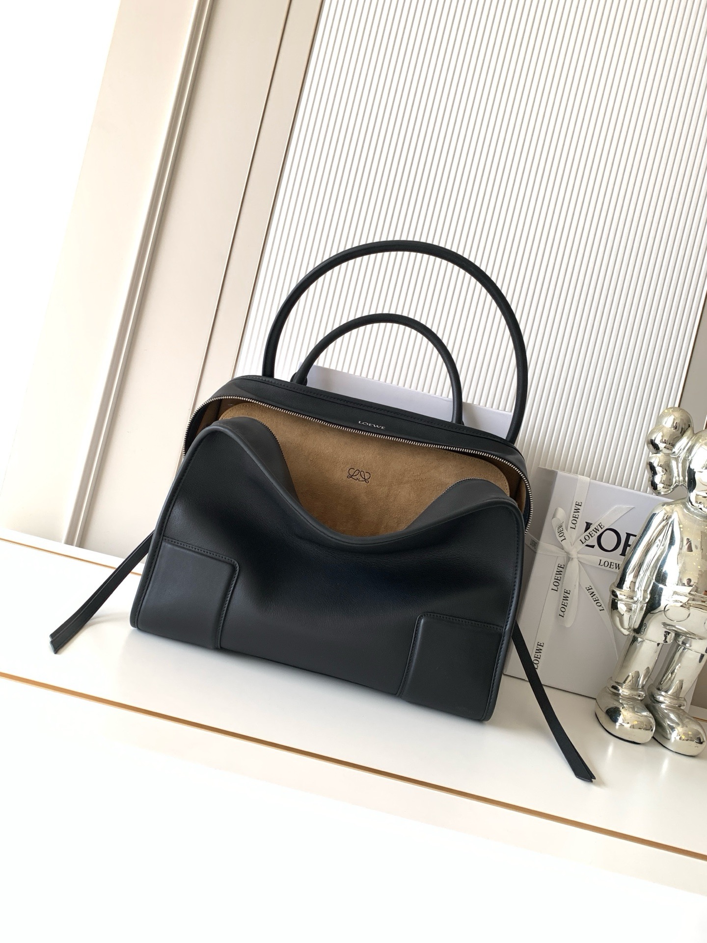 NO:854482,New large size soft cow leather Amazona 180 handbag, same style as Amazona stars  180 reinterprets the legendary handbag in a casual silhouette with a single top handle. The bag features an open design. The main compartment is secured with a hidden buckle and features a detachable shoulder and cross-body strap for a practical style. This large version is made from soft calfskin leather*3  Two ways to carry: Short handle, detachable shoulder and cross-body straps *Zipper with two leather zipper pulls*Two compartments, main compartment with magnetic closure  L embossed brand logo Size 34.5CM～27CM～14CM Style number 9173 Color black, Loewe, loewe, cowhide19860909新款大号柔软牛皮革 Amazona 180 手袋 明星同款Amazona 180重新诠释传奇手袋呈现休闲廓形,搭配单一顶部提手手袋采用开放式设计主隔层以隐藏扣固定搭配可拆卸肩背和斜挎背带打造实用风格.此大号版本采用柔软牛皮革制成*三种携带方式短提手、可拆卸肩背和斜挎背带*拉链配有两个皮革拉链头*两个隔层,主隔层以磁扣开合*内部扁平口袋*左侧D形环可定制*织物衬里*烫金或烫银,Double L 压纹品牌标志 尺寸34.5CM～27CM～14CM 款号9173 颜色黑色,罗意威,loewe,cowhide,Bag