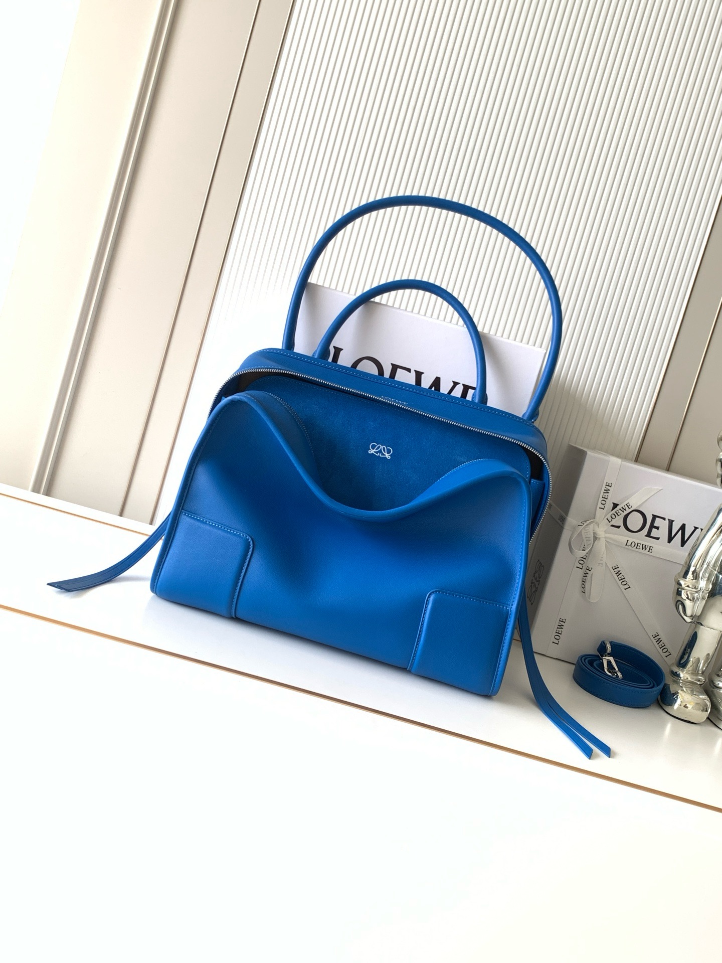 NO:854492,New large size soft cow leather Amazona 180 handbag, same style as Amazona stars  180 reinterprets the legendary handbag in a casual silhouette with a single top handle. The bag features an open design. The main compartment is secured with a hidden buckle and features a detachable shoulder and cross-body strap for a practical style. This large version is made from soft calfskin leather*3  Two ways to carry: Short handle, detachable shoulder and cross-body straps *Zipper with two leather zipper pulls*Two compartments, main compartment with magnetic closure  L embossed brand logo Size 34.5CM～27CM～14CM Style number 9173 Color royal blue, Loewe, loewe, cowhide19860909新款大号柔软牛皮革 Amazona 180 手袋 明星同款Amazona 180重新诠释传奇手袋呈现休闲廓形,搭配单一顶部提手手袋采用开放式设计主隔层以隐藏扣固定搭配可拆卸肩背和斜挎背带打造实用风格.此大号版本采用柔软牛皮革制成*三种携带方式短提手、可拆卸肩背和斜挎背带*拉链配有两个皮革拉链头*两个隔层,主隔层以磁扣开合*内部扁平口袋*左侧D形环可定制*织物衬里*烫金或烫银,Double L 压纹品牌标志 尺寸34.5CM～27CM～14CM 款号9173 颜色皇室蓝,罗意威,loewe,cowhide,Bag