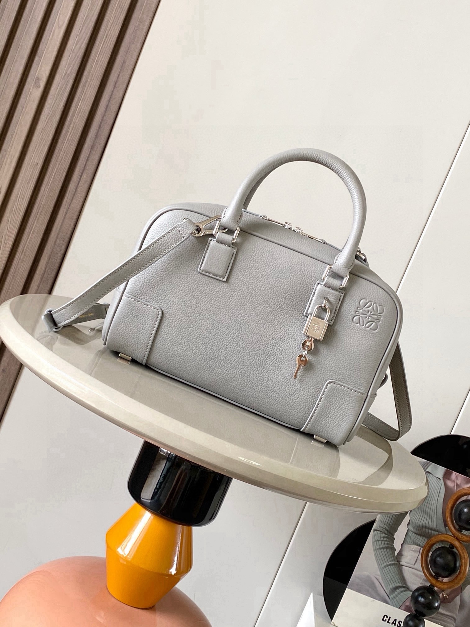 NO:854500,Amazona 23 Bag in Nappa Cow Leather The Amazona is LOEWE's iconic bag, originally launched in the 1970s as a top-handle soft-structure bag. This Nappa cow leather version is updated with refined proportions and details, including an Anagram  Engraved padlock * Cross-body, shoulder or top handle carry * Detachable and adjustable shoulder strap * Dual zipper closure * Cow leather zipper pull * Internal zip compartment and snap-fastened slip pocket * Mini pocket for padlock keys * Protective metal feet at base * Can be customized with shoulder strap and personalized charms * Gold suede lining * Anagram embossed  Size 23cm～10cm～15cm Style No. 9078 Color Gray Li, Loewe, loewe, loewe, cowhide19860909纳帕牛皮革 Amazona 23 手袋Amazona 是 LOEWE 的标志性手袋,最初于1970年代作为顶部提手软结构手袋推出这款纳帕牛皮革版本更新了精致的比例和细节,包括一个 Anagram 雕刻挂锁＊斜挎、肩背或顶部提手携带＊可拆卸可调节肩带＊双拉链开合＊牛皮革拉链头＊内部拉链隔层和按扣固定的插袋＊用于存放挂锁钥匙的迷你口袋＊底部保护性金属脚＊可以使用肩带和个性化挂饰进行定制＊金色绒面革衬里＊ Anagram 压纹 尺寸23cm～10cm～15cm 款号9078 颜色灰色荔,罗意威,loewe,loewe,cowhide,Bag