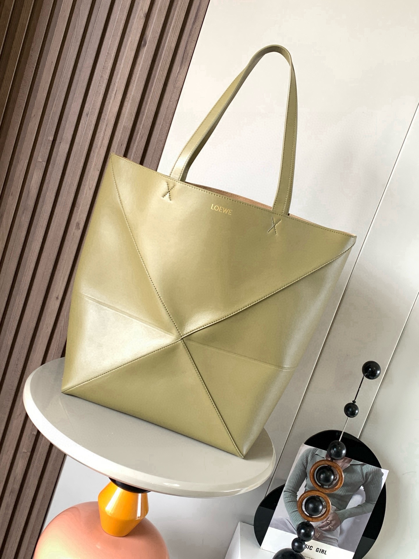 NO:854576,Large new shiny cow leather shopping bag puzzle Fold handbag large geometric pattern It has been a long time since I have seen such a practical and design tote bag. This continues the geometric aesthetics of the Puzzle series and is inspired by origami bags. This Puzzle Fold tote  I freely switch between three-dimensional and flat upper body sizes for your reference. The large size has a more friendly capacity, and the small size is very cute. The leather is very delicate and shiny. It is super light in weight. In addition, it can be folded, which is perfect for commuting with a computer, or for people like me who often travel on business and can easily store it in their luggage. Puzzle  The Fold handbag draws inspiration from the geometric lines of the brand's classic handbag series and uses creative ingenuity to reinterpret it into a fashionable tote bag that can be completely folded and is a good travel companion. This large version is made of soft glossy cowhide. Size 42CM～41CM～18CM. Style No. 9033. Color: olive, Loewe, totes, cowhide.19860909大号新款亮面牛皮革购物袋puzzle Fold手袋大号几何图形玩出花了很久没见过这么实用又设计感满满的托特包了这款延续了Puzzle系列的几何美学以折纸包为灵感,让这只 Puzzle Fold tote 在立体和平面随意切换上身了两个尺码给大家参考哦大号容量更友好,小号很可爱,皮质都很细腻光泽本身自重超轻,外加可以折叠太适合平时带电脑通勤,或是像我一样经常出差旅行不费力的收纳进行李箱,Puzzle Fold手袋从品牌经典手袋系列的几何线条汲取灵感运用创意巧思将其重新诠释为一款时尚的托特袋,能完全折叠是旅行良伴.这个大号版本采用柔软的亮面牛皮革打造 尺寸42CM～41CM～18CM 款号9033 颜色橄榄色,罗意威,loewe,totes,cowhide,Bag