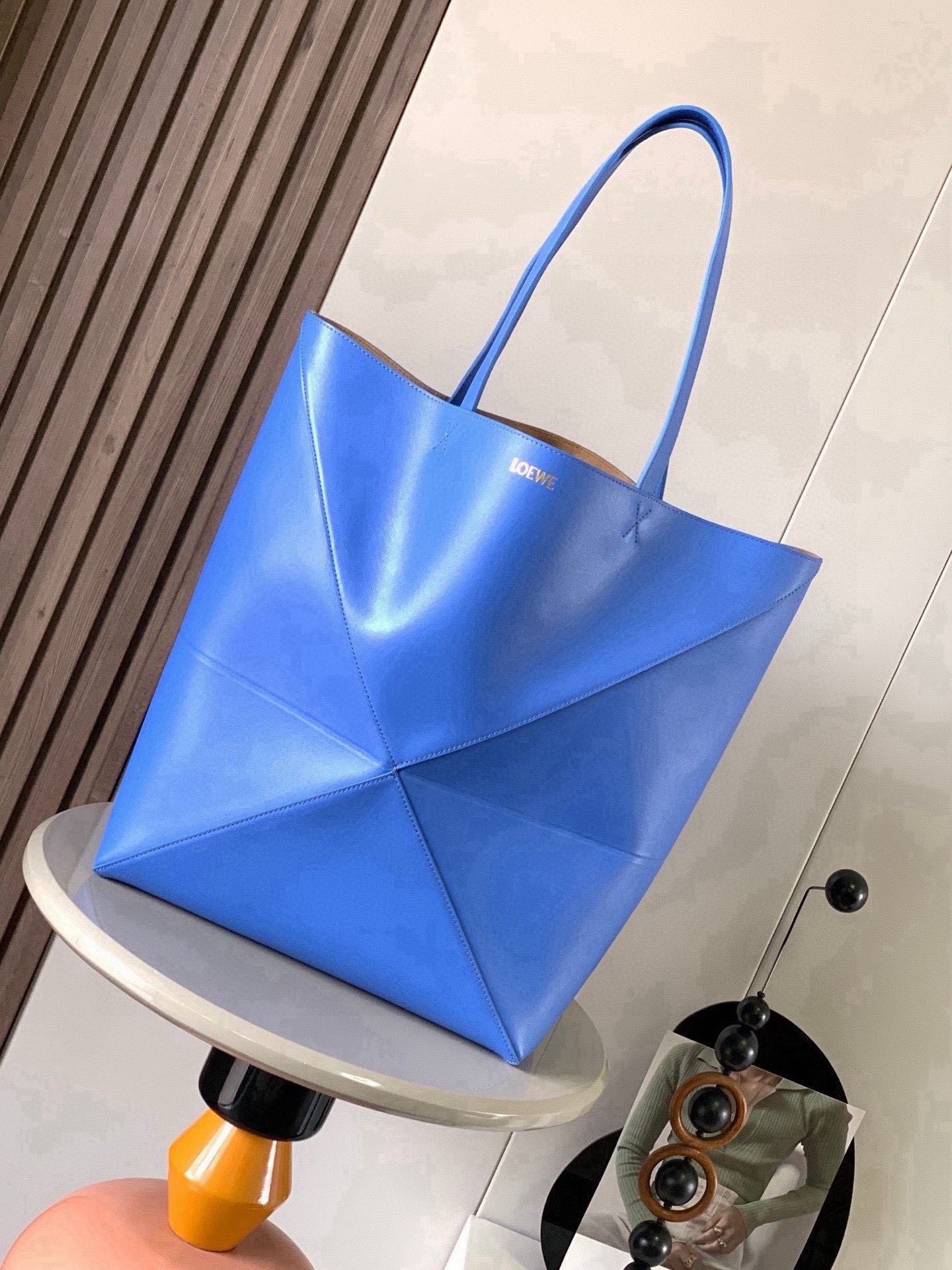 NO:854597,Large new shiny cow leather shopping bag puzzle Fold handbag large geometric pattern It has been a long time since I have seen such a practical and design tote bag. This continues the geometric aesthetics of the Puzzle series and is inspired by origami bags. This Puzzle Fold tote  I freely switch between three-dimensional and flat upper body sizes for your reference. The large size has a more friendly capacity, and the small size is very cute. The leather is very delicate and shiny. It is super light in weight. In addition, it can be folded, which is perfect for commuting with a computer, or for people like me who often travel on business and can easily store it in their luggage. Puzzle  The Fold handbag draws inspiration from the geometric lines of the brand's classic handbag series and uses creative ingenuity to reinterpret it into a fashionable tote bag that can be completely folded and is a good travel companion. This large version is made of soft glossy cowhide. Size 42CM～41CM～18CM. Style No. 9033. Color blue, Loewe, totes, cowhide.19860909大号新款亮面牛皮革购物袋puzzle Fold手袋大号几何图形玩出花了很久没见过这么实用又设计感满满的托特包了这款延续了Puzzle系列的几何美学以折纸包为灵感,让这只 Puzzle Fold tote 在立体和平面随意切换上身了两个尺码给大家参考哦大号容量更友好,小号很可爱,皮质都很细腻光泽本身自重超轻,外加可以折叠太适合平时带电脑通勤,或是像我一样经常出差旅行不费力的收纳进行李箱,Puzzle Fold手袋从品牌经典手袋系列的几何线条汲取灵感运用创意巧思将其重新诠释为一款时尚的托特袋,能完全折叠是旅行良伴.这个大号版本采用柔软的亮面牛皮革打造 尺寸42CM～41CM～18CM 款号9033 颜色蓝色,罗意威,loewe,totes,cowhide,Bag