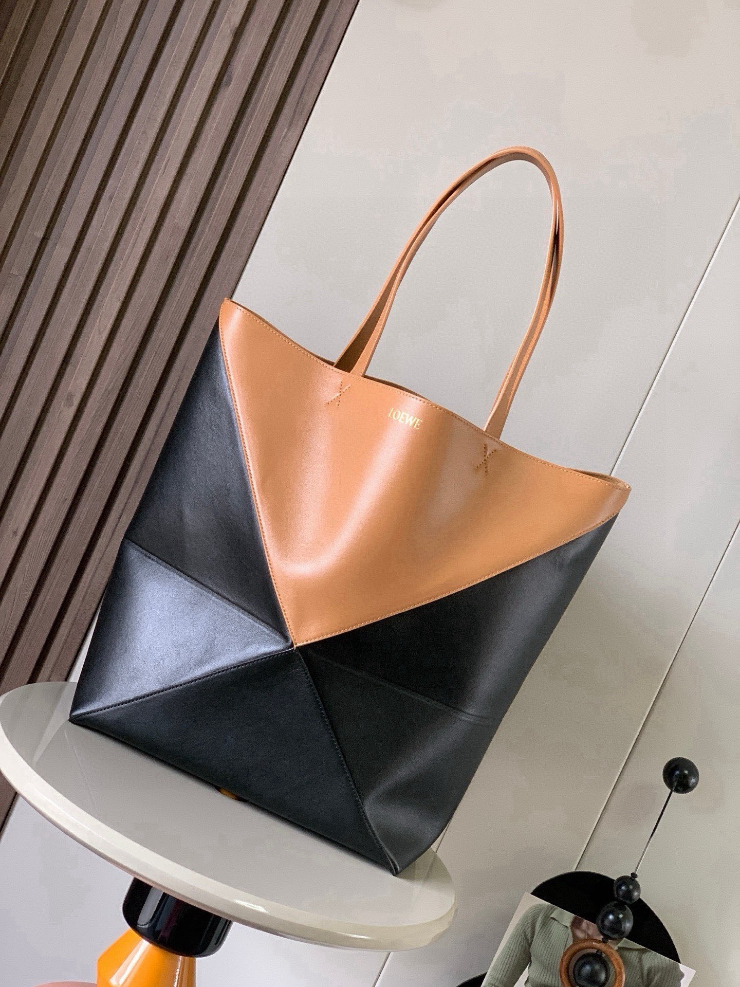 NO:854631,Large new shiny cow leather shopping bag puzzle Fold handbag large geometric pattern It has been a long time since I have seen such a practical and design tote bag. This continues the geometric aesthetics of the Puzzle series and is inspired by origami bags. This Puzzle Fold tote  I freely switch between three-dimensional and flat upper body sizes for your reference. The large size has a more friendly capacity, and the small size is very cute. The leather is very delicate and shiny. It is super light in weight. In addition, it can be folded, which is perfect for commuting with a computer, or for people like me who often travel on business and can easily store it in their luggage. Puzzle  The Fold handbag draws inspiration from the geometric lines of the brand's classic handbag series and uses creative ingenuity to reinterpret it into a fashionable tote bag that can be completely folded and is a good travel companion. This large version is made of soft glossy cowhide. Size 42CM ~ 41CM ~ 18CM. Style number 9033. Color: warm sand yellow and black, Loewe, loewe, totes, cowhide19860909大号新款亮面牛皮革购物袋puzzle Fold手袋大号几何图形玩出花了很久没见过这么实用又设计感满满的托特包了这款延续了Puzzle系列的几何美学以折纸包为灵感,让这只 Puzzle Fold tote 在立体和平面随意切换上身了两个尺码给大家参考哦大号容量更友好,小号很可爱,皮质都很细腻光泽本身自重超轻,外加可以折叠太适合平时带电脑通勤,或是像我一样经常出差旅行不费力的收纳进行李箱,Puzzle Fold手袋从品牌经典手袋系列的几何线条汲取灵感运用创意巧思将其重新诠释为一款时尚的托特袋,能完全折叠是旅行良伴.这个大号版本采用柔软的亮面牛皮革打造 尺寸42CM～41CM～18CM 款号9033 颜色暖沙黄黑,罗意威,loewe,totes,cowhide,Bag