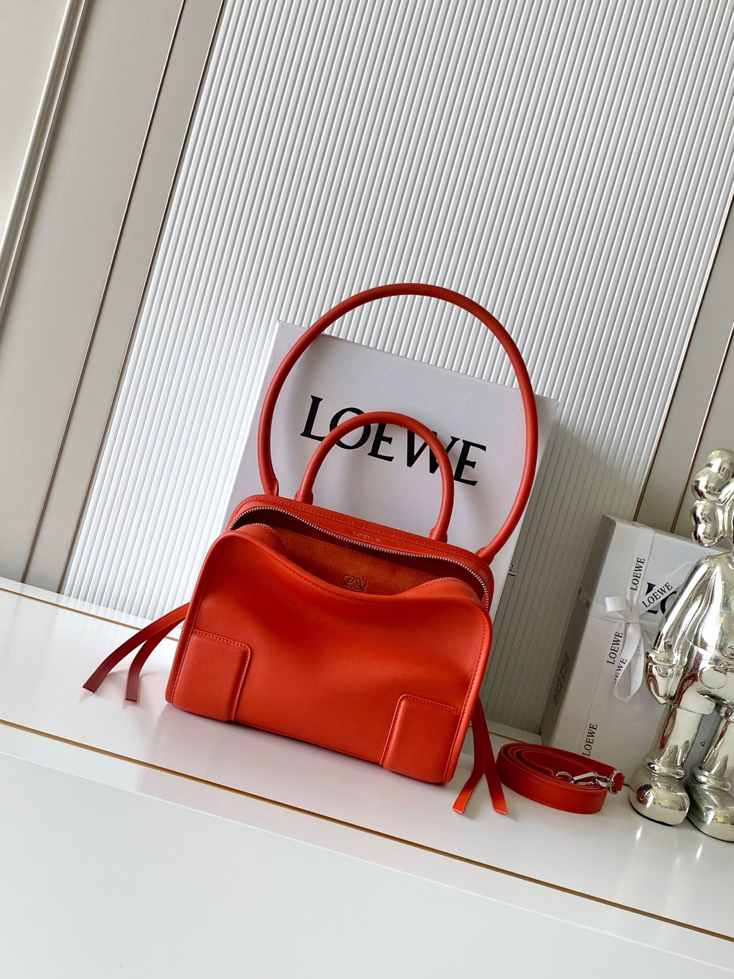 NO:880448,New small size soft cow leather Amazona 180 handbag, same style as Amazona stars  180 reinterprets the legendary handbag in a casual silhouette with a single top handle. The bag features an open design. The main compartment is secured with a hidden buckle and features a detachable shoulder and cross-body strap for a practical style. This small version is made from soft calfskin leather*3  Two ways to carry: Short handle, detachable shoulder and cross-body straps *Zipper with two leather zipper pulls*Two compartments, main compartment with magnetic closure  L embossed brand logo Size 24.5CM～18.5CM～10CM Style number 9174 Color sunrise orange, Loewe, loewe, cowhide19860909新款小号柔软牛皮革 Amazona 180 手袋 明星同款Amazona 180重新诠释传奇手袋呈现休闲廓形,搭配单一顶部提手手袋采用开放式设计主隔层以隐藏扣固定搭配可拆卸肩背和斜挎背带打造实用风格.此小号版本采用柔软牛皮革制成*三种携带方式短提手、可拆卸肩背和斜挎背带*拉链配有两个皮革拉链头*两个隔层,主隔层以磁扣开合*内部扁平口袋*左侧D形环可定制*织物衬里*烫金或烫银,Double L 压纹品牌标志 尺寸24.5CM～18.5CM～10CM 款号9174 颜色日出橙,罗意威,loewe,cowhide,Bag