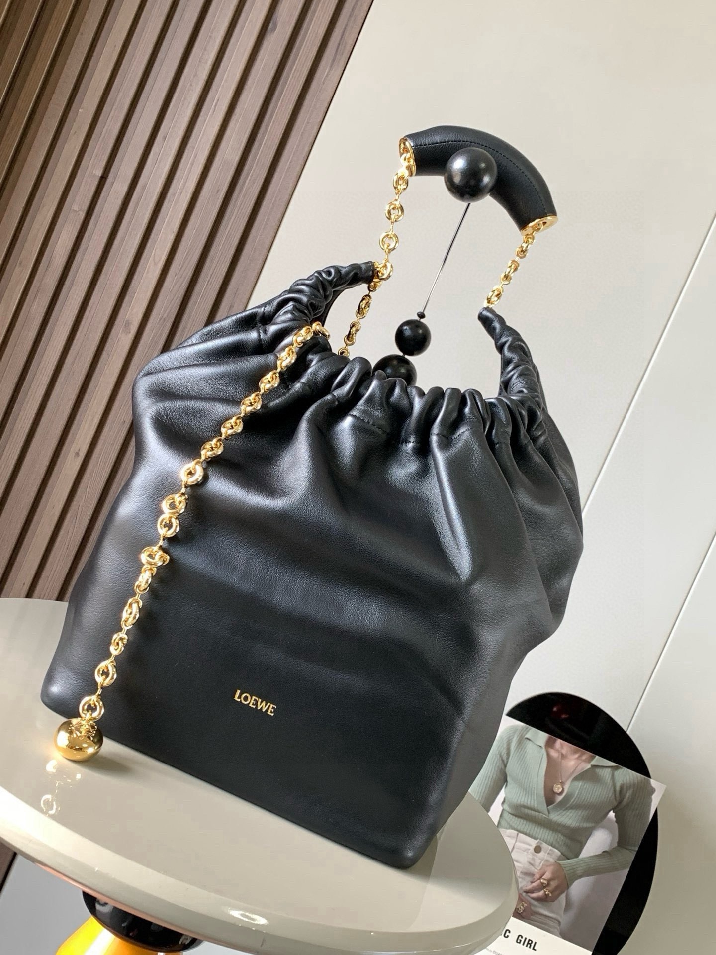 NO:880423,[Celebrity Style] Medium Nappa Lamb Leather Squeeze Handbag is a refined and feminine new handbag. The newly released Squeeze Handbag is made of soft and silky Mellow Nappa lambskin. The unlined structure effectively reduces the weight of the bag and makes it lighter in appearance. The crescent-shaped bag mouth is closed with elegant ruffles, creating a relaxed and casual attitude. Another highlight of this bag is the ergonomic Squeeze  The airbag handle is paired with a delicate donut chain made of brass. The length can be adjusted through the chain link or an extension chain can be added to realize different carrying methods such as hand carry, shoulder carry, and crossbody. The airbag handle can slide freely to improve comfort. An Anagram Pebble pendant is embellished at the bottom of the chain to add smart details to the bag. Size 34CM～33CM～13.5CM Style No. 9041 Color Black, Loewe, Loewe, Sheepskin19860909【明星同款】中号纳帕羊皮革Squeeze手袋是款精致而柔美的全新手袋全新发布的 Squeeze 手袋采用柔软丝滑的Mellow纳帕小羊皮制作而成无衬里结构有效减轻包身自重观感上也更为轻盈弯月形包口以优雅的褶边收口,营造出轻松又随性的态度这款包包还有一大亮点是符合人体工程学的 Squeeze 气囊手柄搭配黄铜打造的精美甜甜圈链条可通过链环调节长短或添加延长链,实现手拎、肩背、斜挎等不同背法气囊手柄可自由滑动位置以提升舒适度链条底部点缀一枚 Anagram Pebble 吊坠,为包包增添灵动细节 尺寸34CM～33CM～13.5CM 款号9041 颜色黑色,罗意威,loewe,sheepskin,Bag
